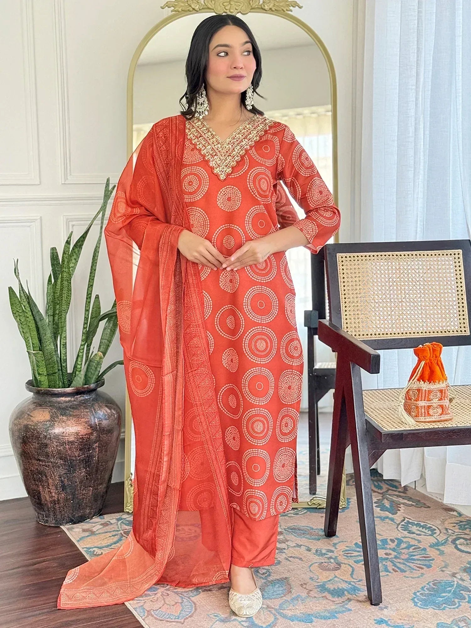Orange printed salwar kameez with gold embroidery, paired with matching dupatta and ethnic jewelry