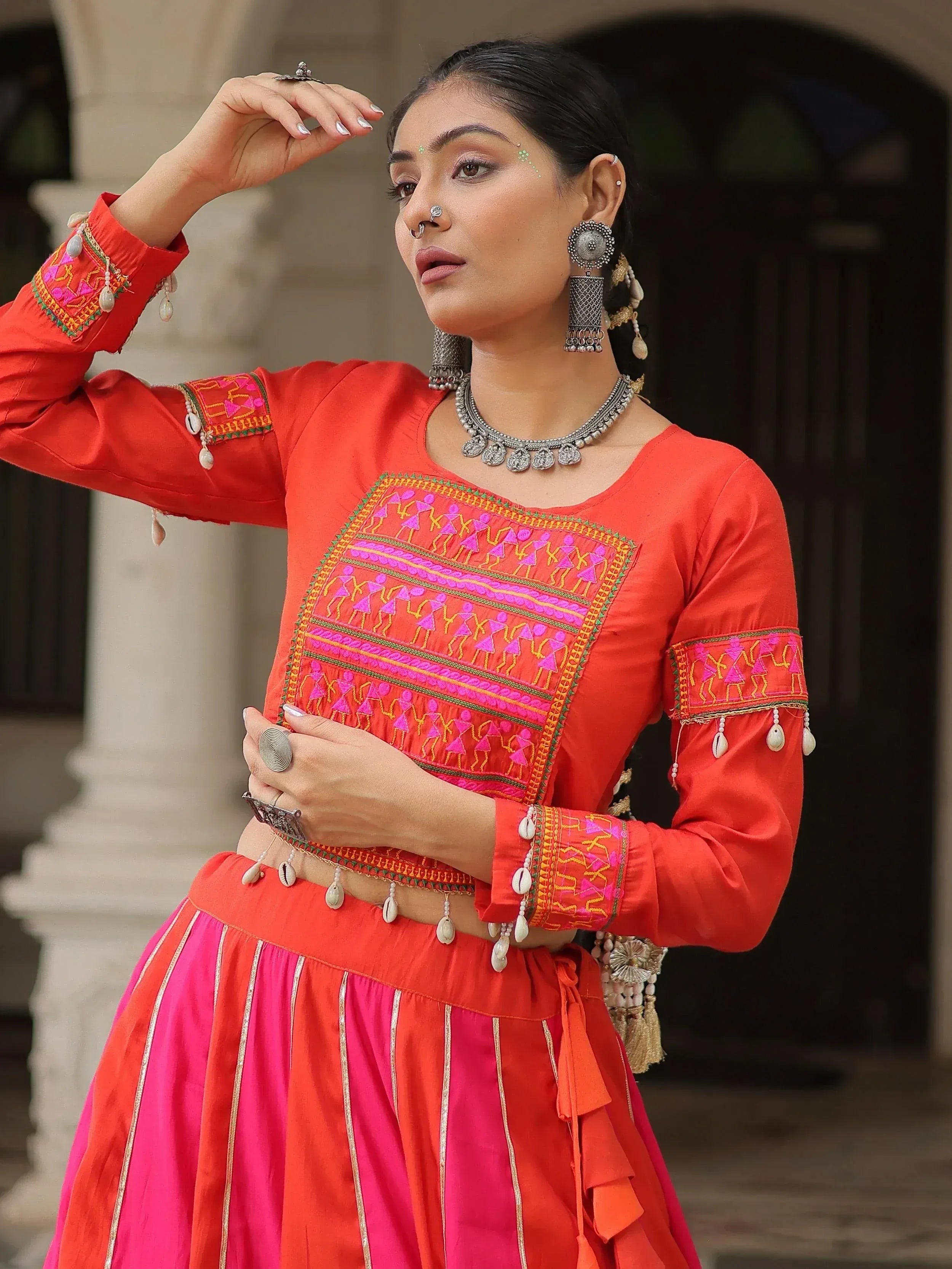 Vibrant red and pink ethnic wear with mirror work, embroidery, and traditional jewelry for festive occasions