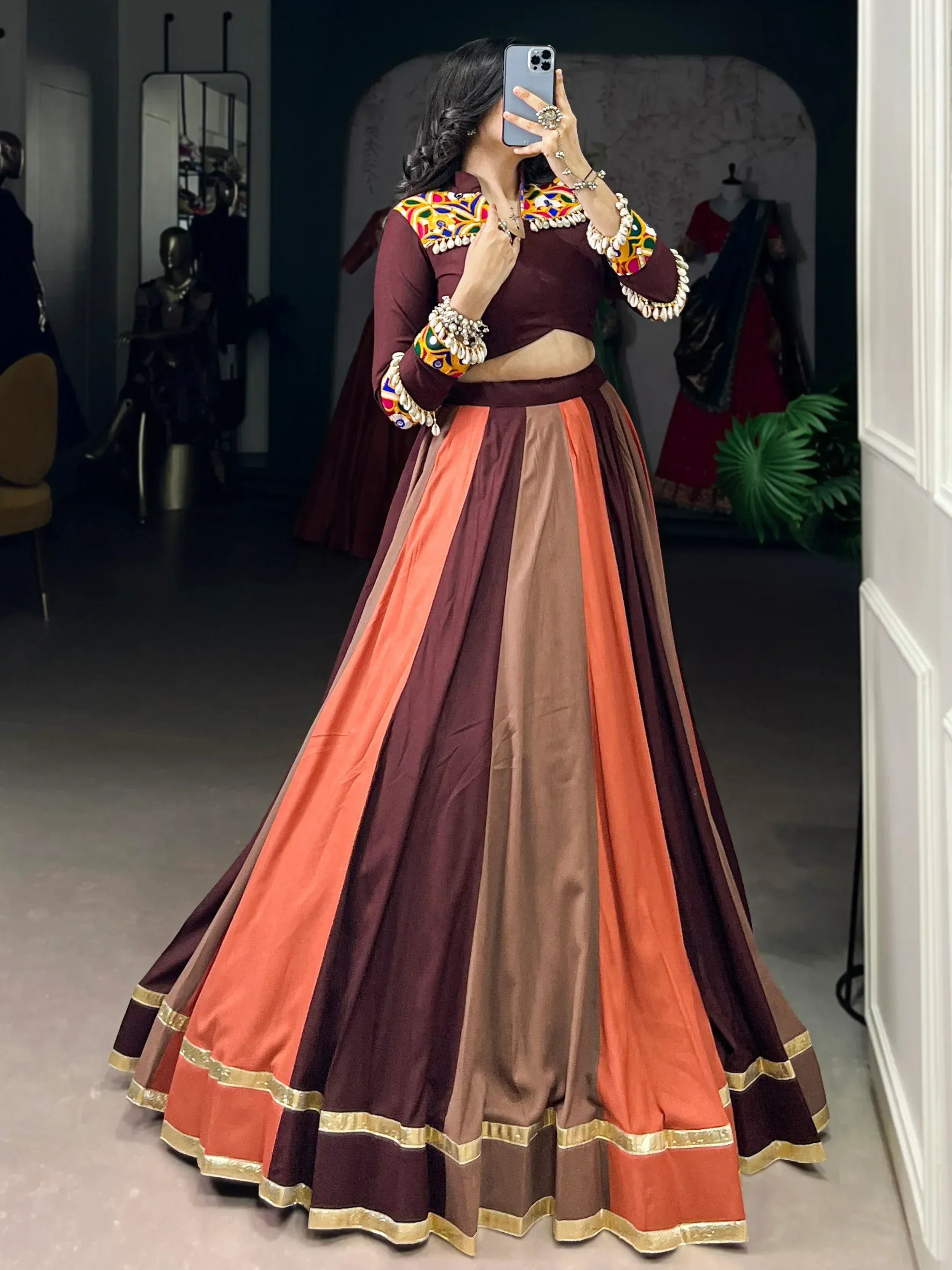 Maroon and orange ethnic lehenga choli with colorful mirror work and gold trim, perfect for Indian weddings or festivals.