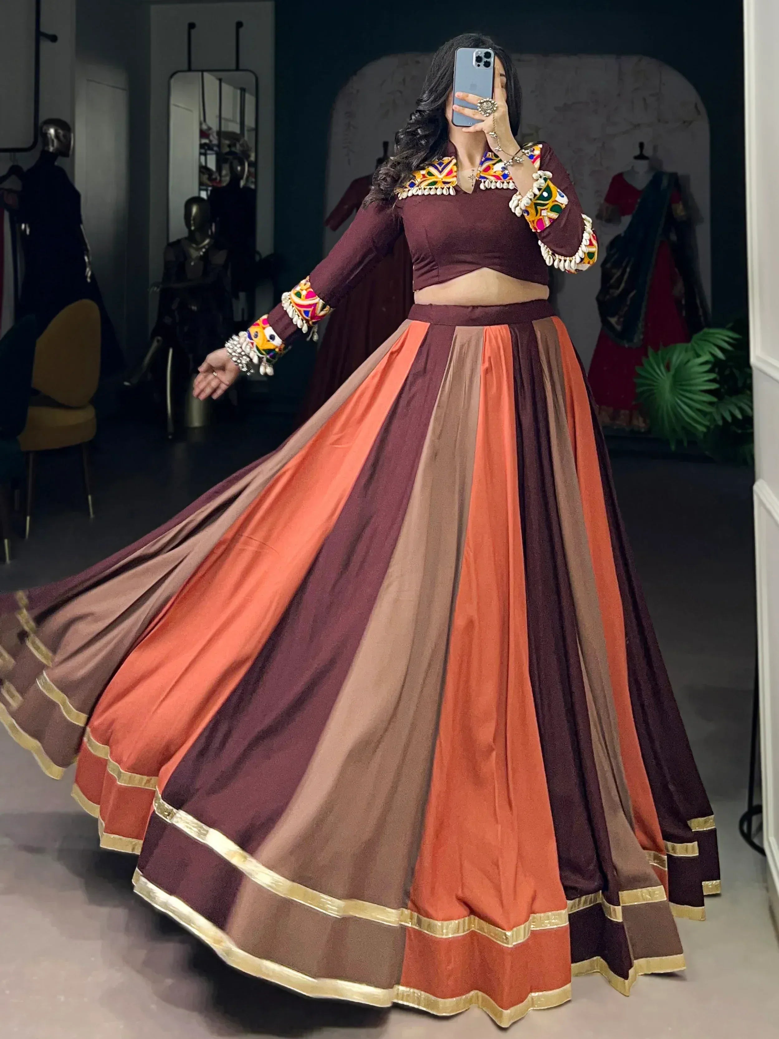 Maroon and orange ethnic lehenga choli with colorful mirror work and gold trim, perfect for Indian weddings or festivals.