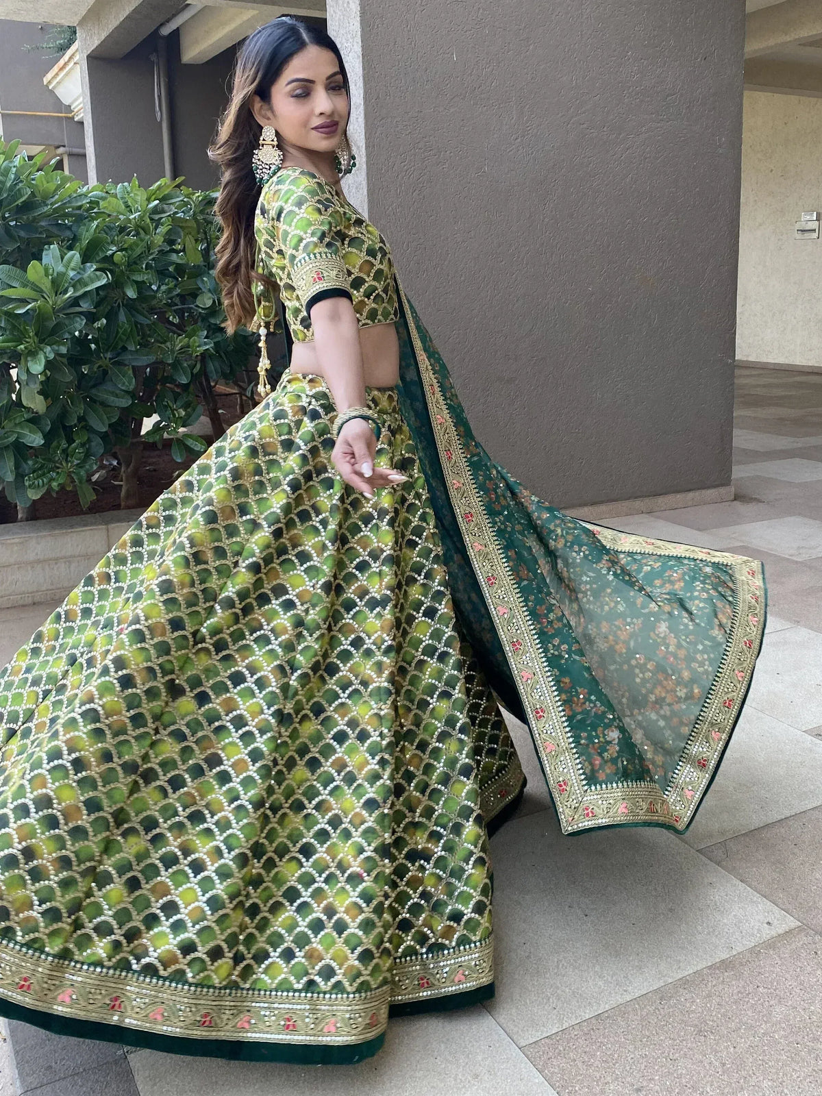 Green and gold designer lehenga choli with intricate embroidery and floral dupatta, perfect for Indian ethnic occasions.