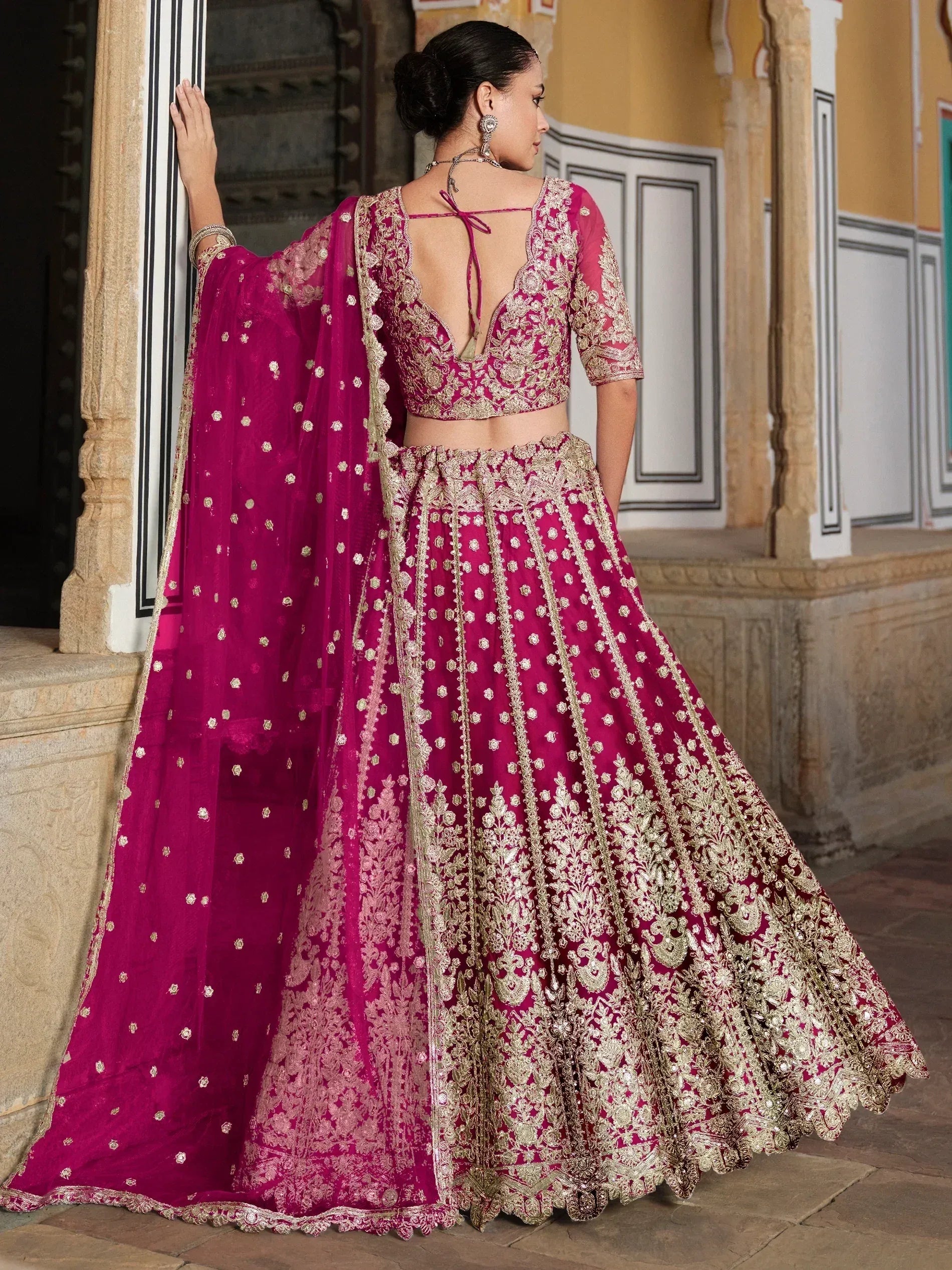 Fuchsia designer lehenga choli with gold embroidery, perfect for Indian weddings and festive occasions.