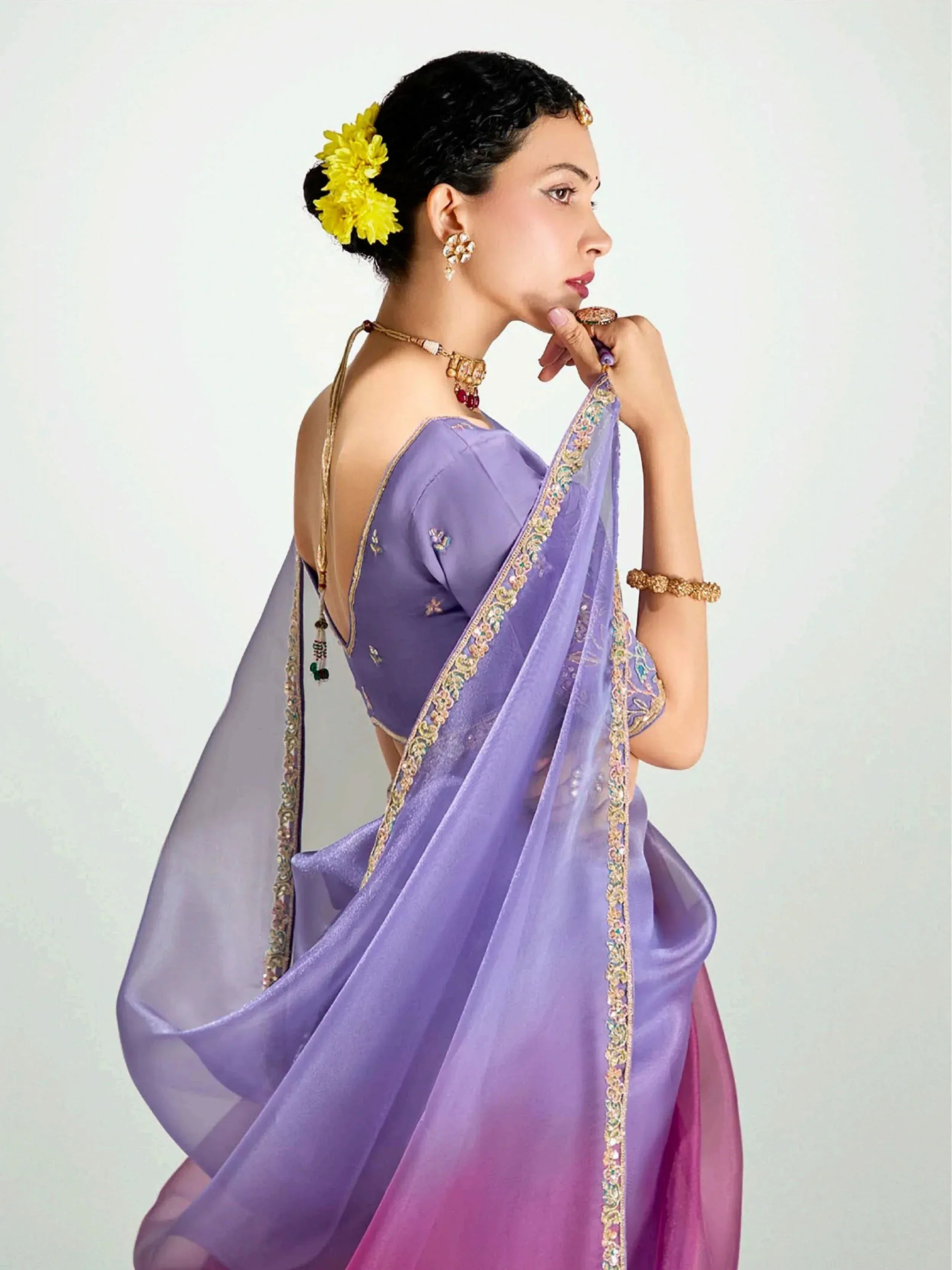 Elegant purple saree with gold embroidery, floral hair accessory, and traditional jewelry for Indian ethnic wear.