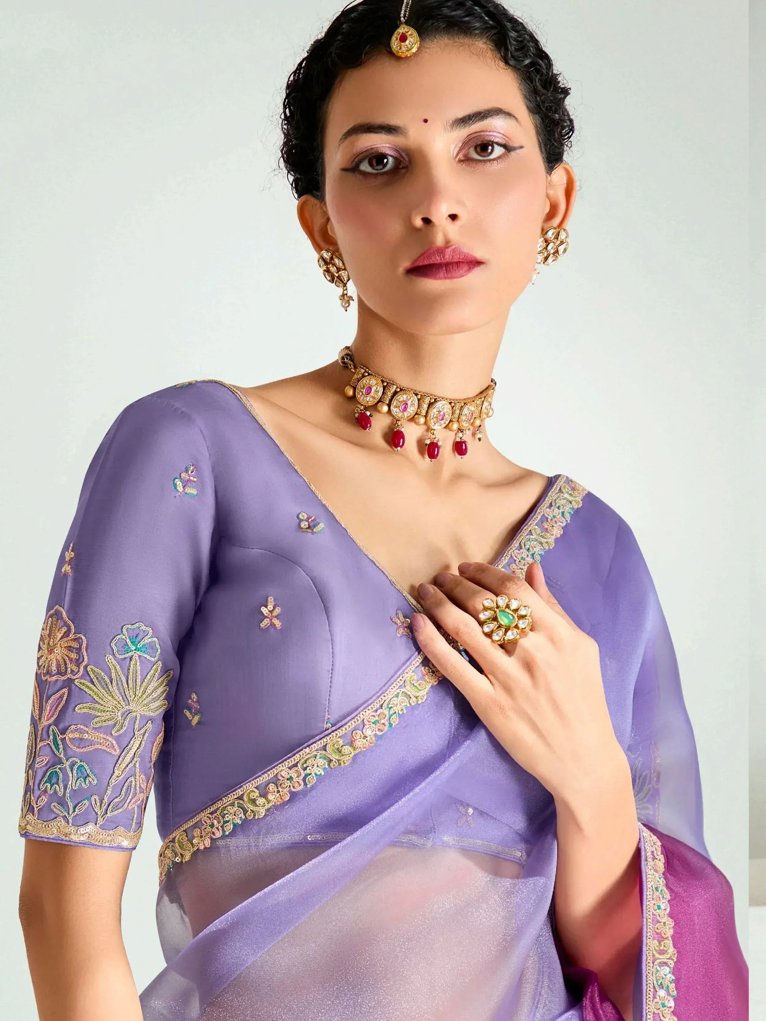 Lavender embroidered saree with floral detailing, paired with traditional Indian jewelry for ethnic wear.