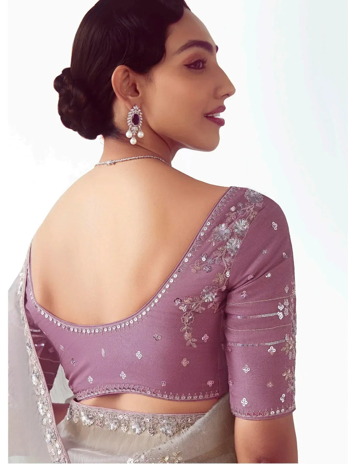 Elegant mauve saree blouse with floral sequin embroidery and open back design, paired with statement earrings