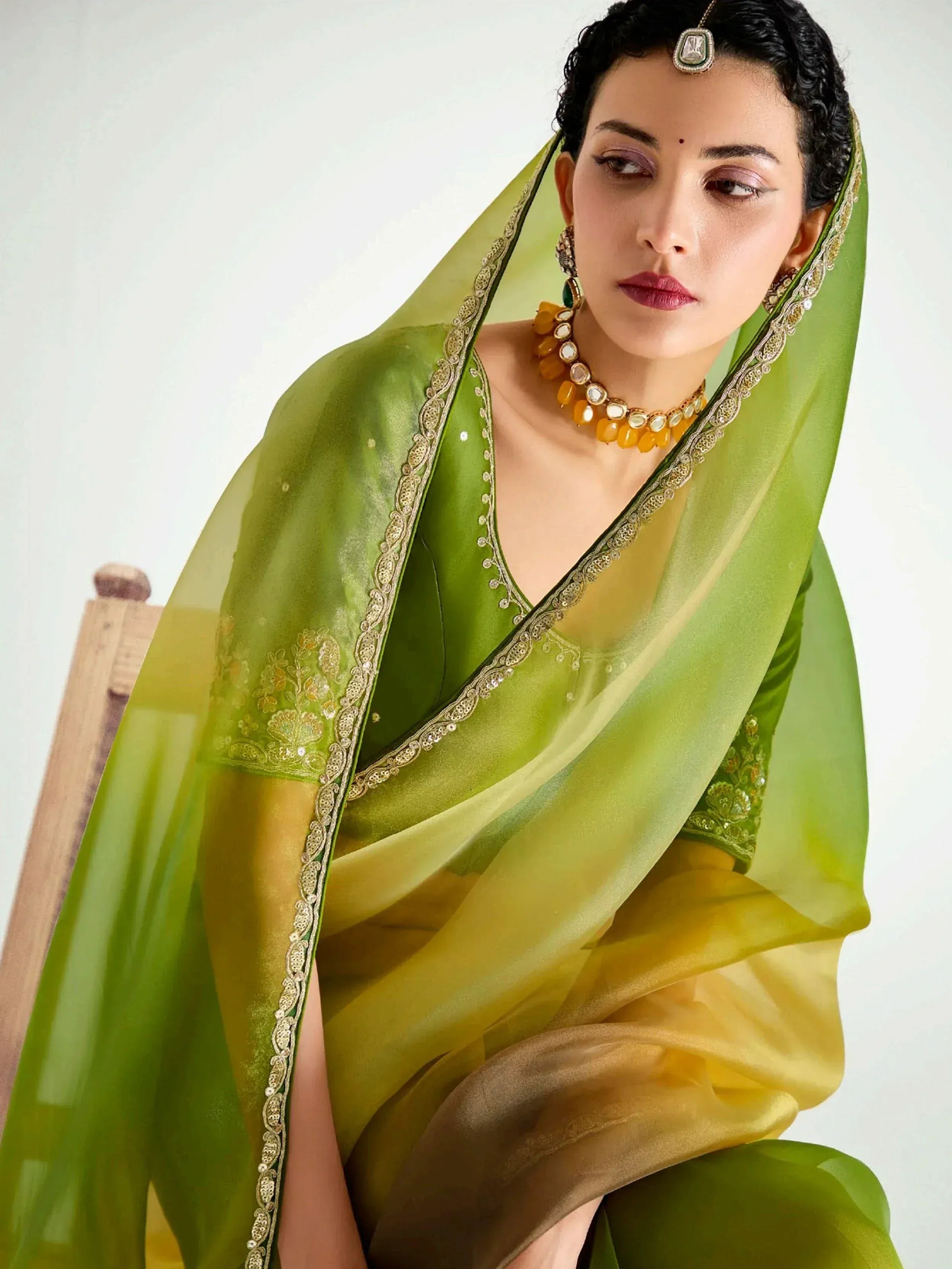 Green and yellow Indian ethnic saree with gold embroidery and traditional jewelry