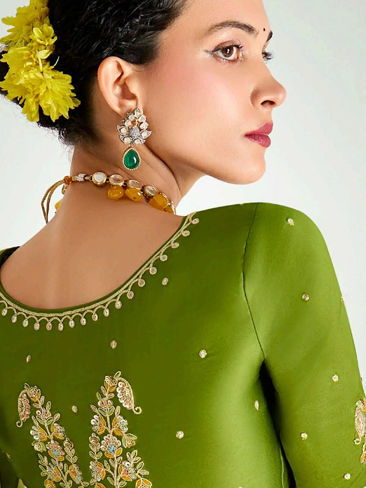Green ethnic kurti with floral embroidery, statement earrings, and yellow flower hair accessory