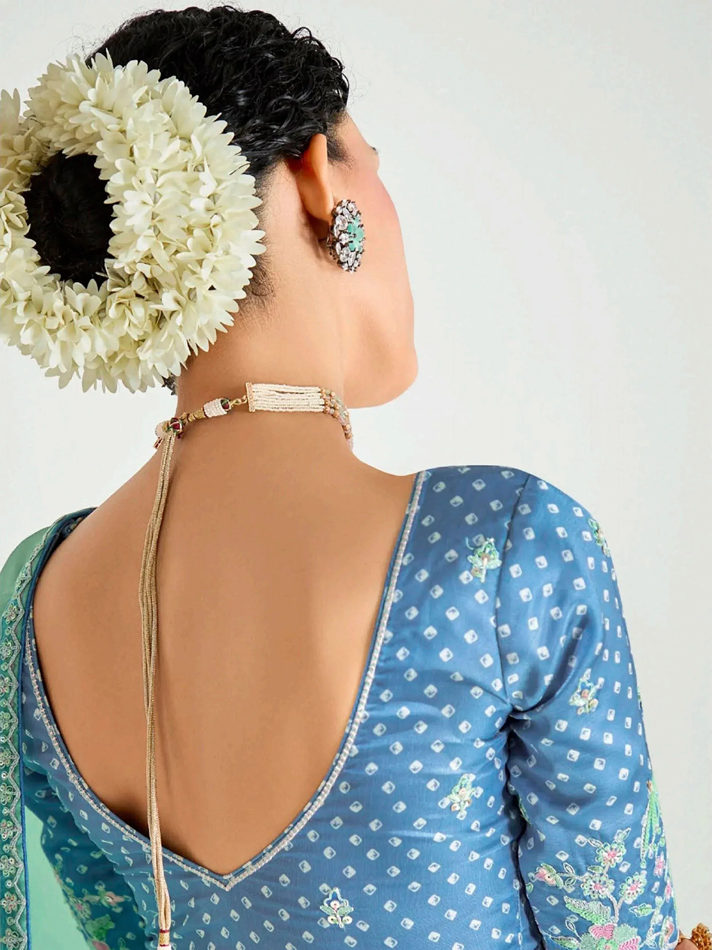 Blue embroidered ethnic blouse with back cutout, floral hair accessory, and beaded choker necklace