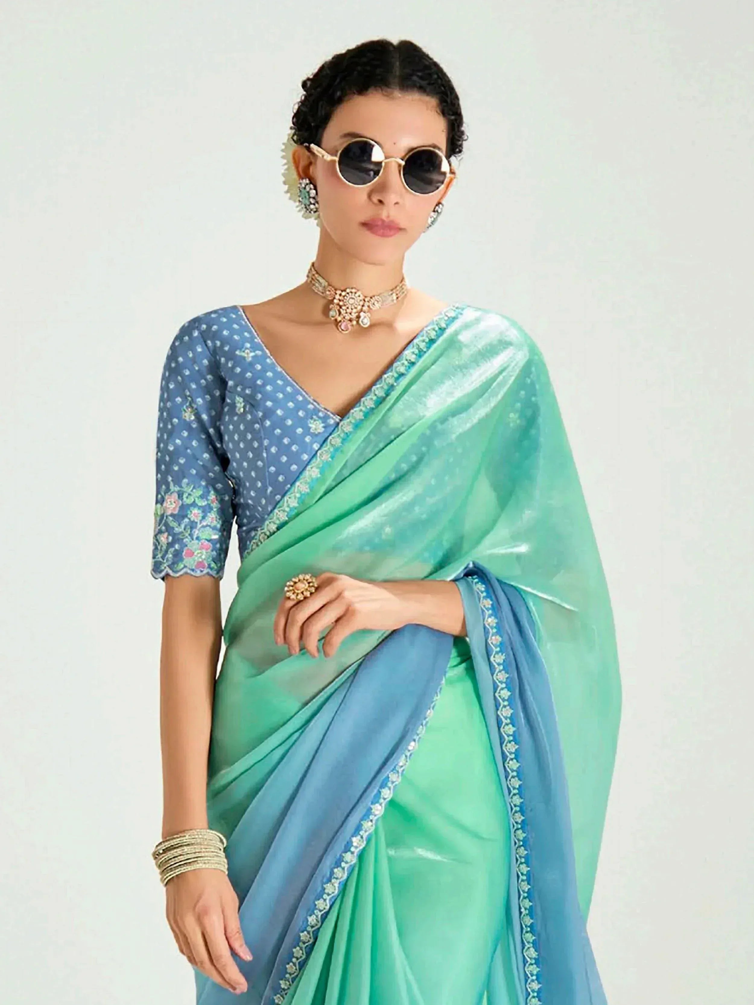 Woman in mint green and blue designer saree with floral blouse, perfect for Indian ethnic wear occasions.