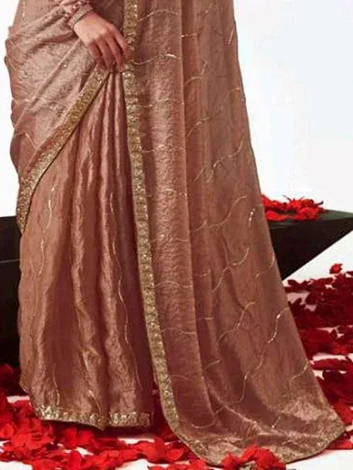 Elegant brown saree with gold embroidery and border, styled with red rose petals for festive occasions