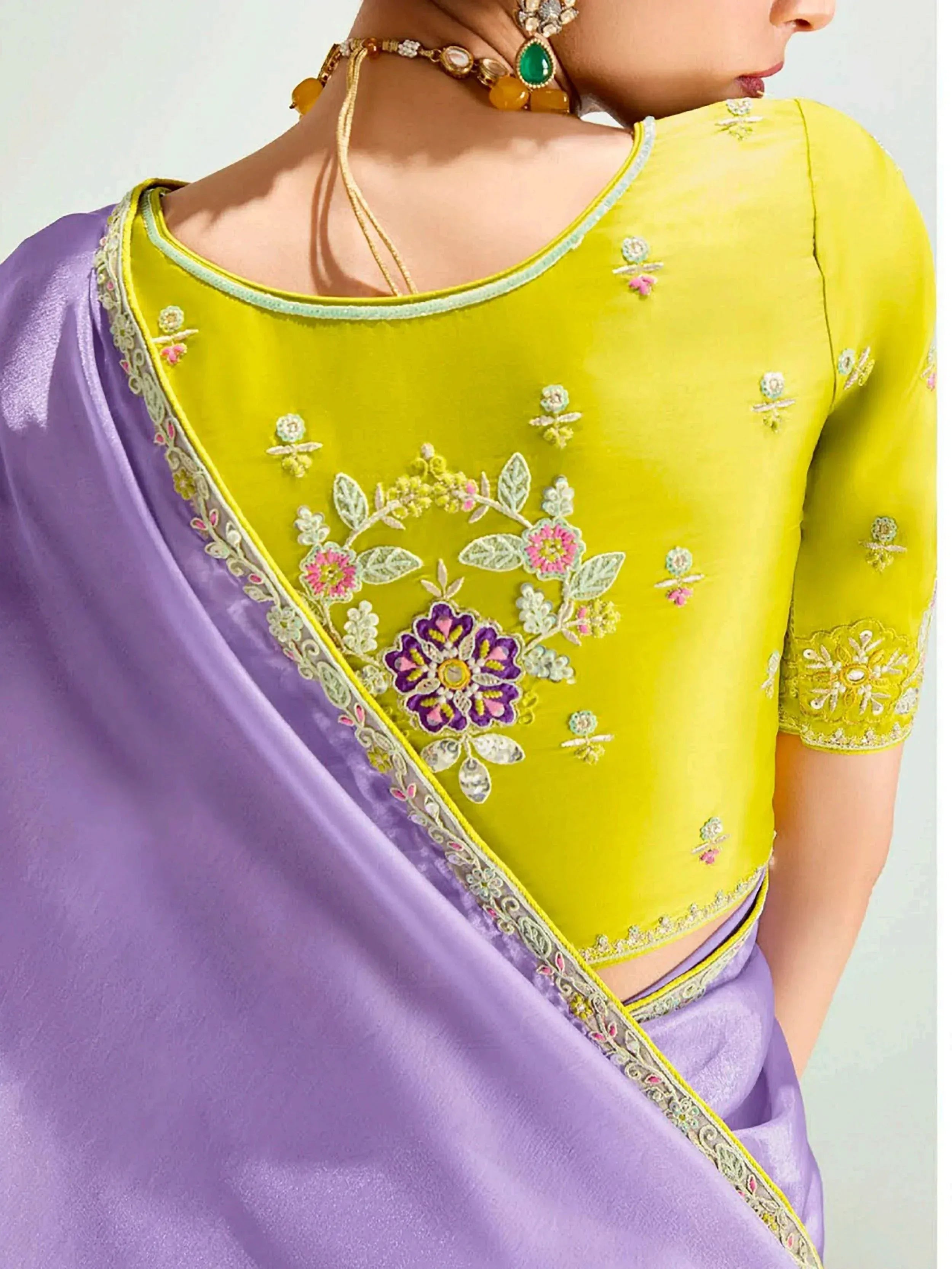 Yellow embroidered blouse with purple saree, floral designs, and traditional Indian jewelry