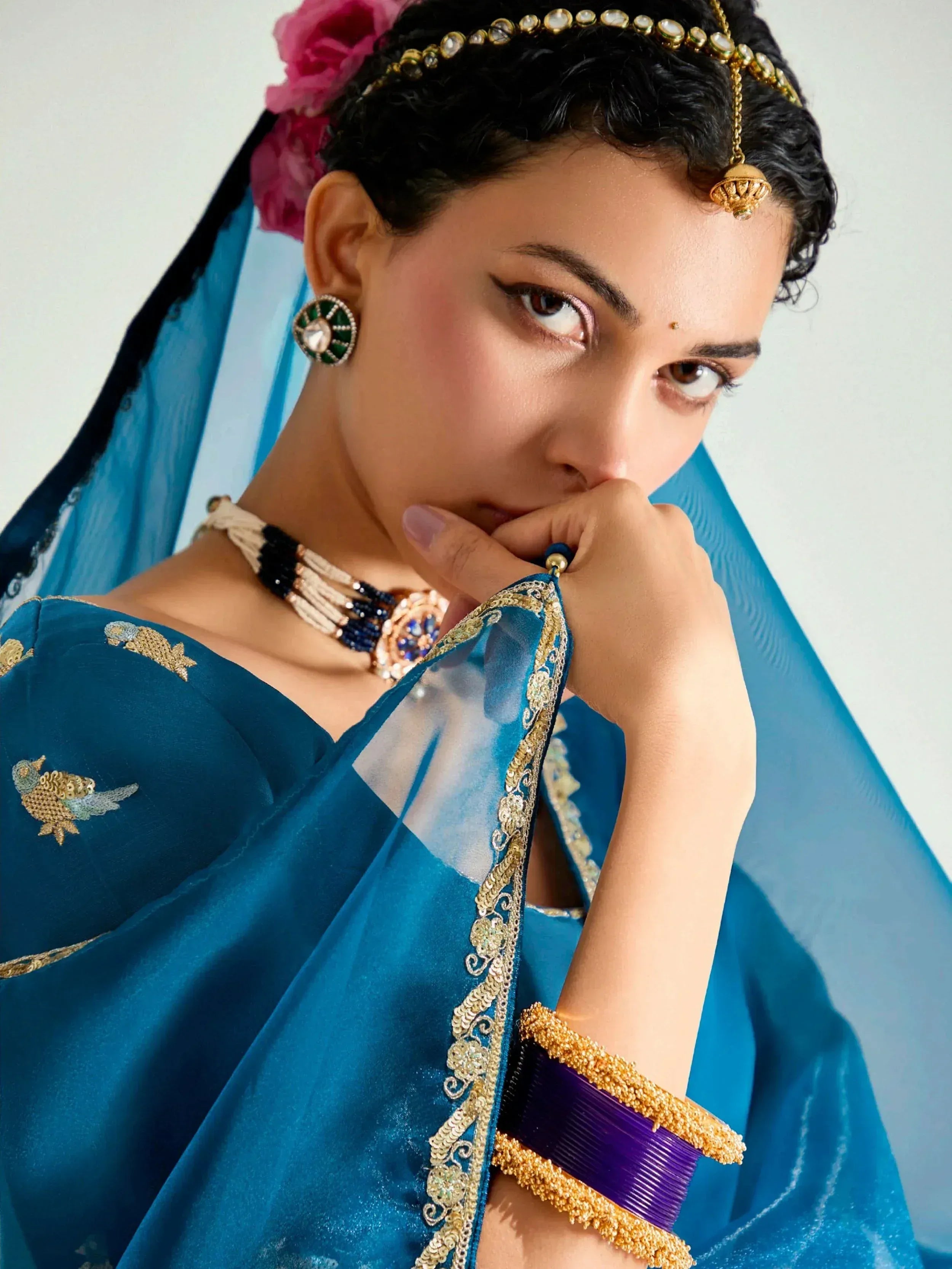 Woman in blue embroidered saree with gold jewelry and floral hair accessory, Indian ethnic wear