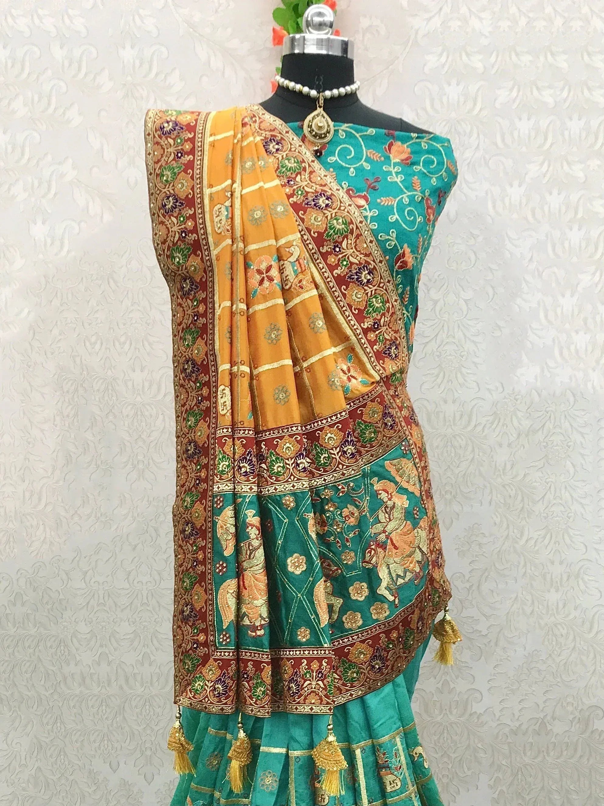 Teal and mustard Indian saree with intricate floral and figurative embroidery, tassels, and border detailing