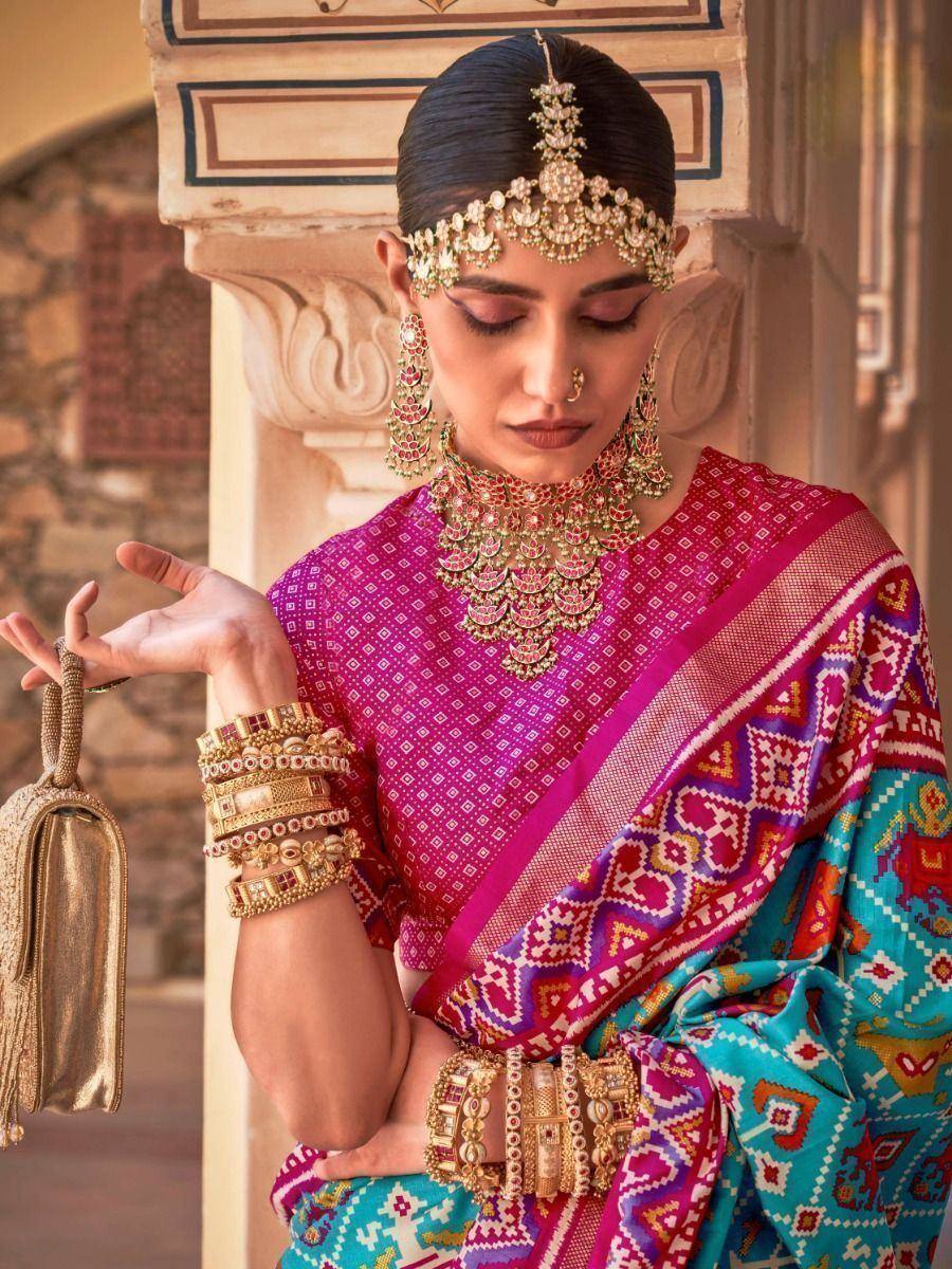 Woman in vibrant pink and teal ethnic saree with traditional jewelry, perfect for Indian festive occasions