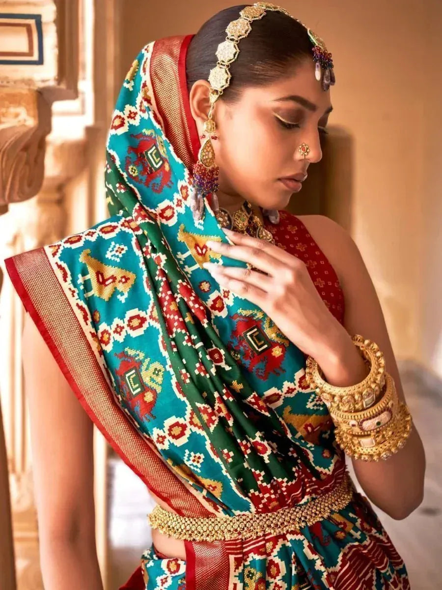 Woman in vibrant Indian ethnic saree with gold jewelry and traditional headpiece