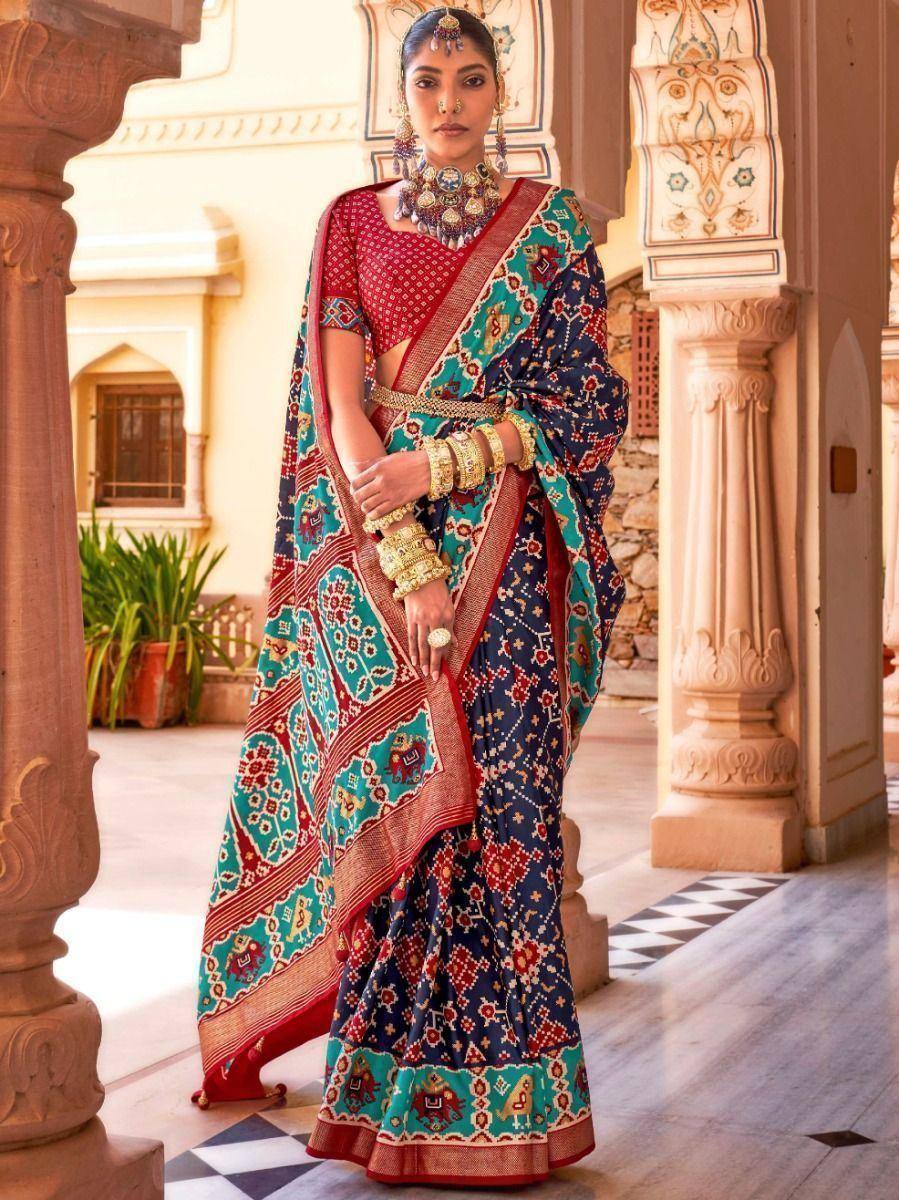 Woman in vibrant Indian saree with elephant print, traditional jewelry, and red blouse, styled for ethnic occasions