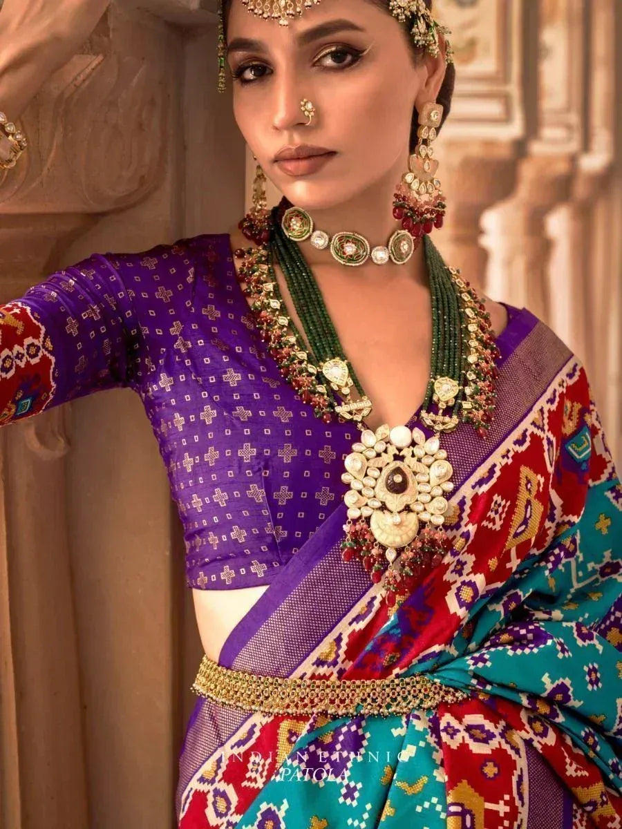 Woman in vibrant Indian ethnic saree with purple blouse, colorful patterns, and traditional jewelry