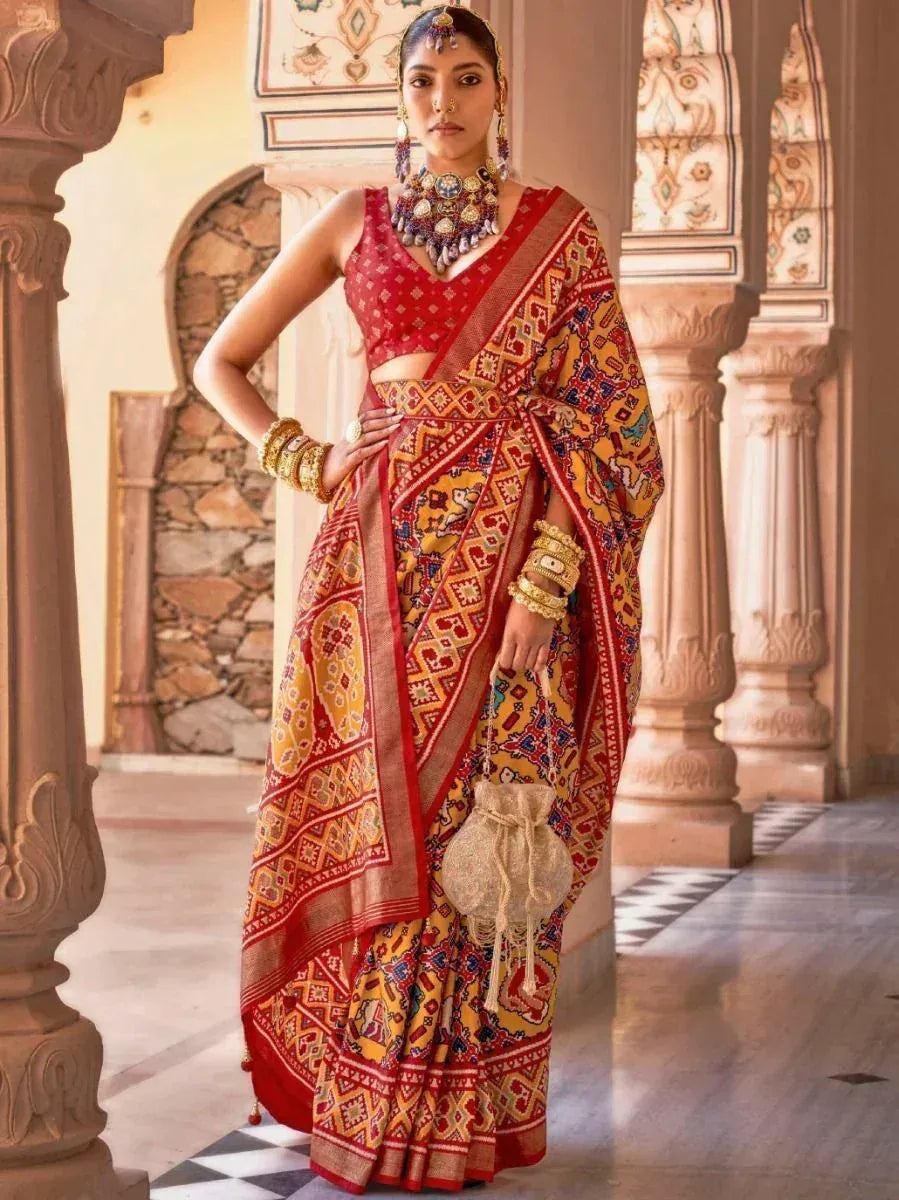 Woman in vibrant red and yellow printed saree with ethnic jewelry, perfect for Indian festive occasions