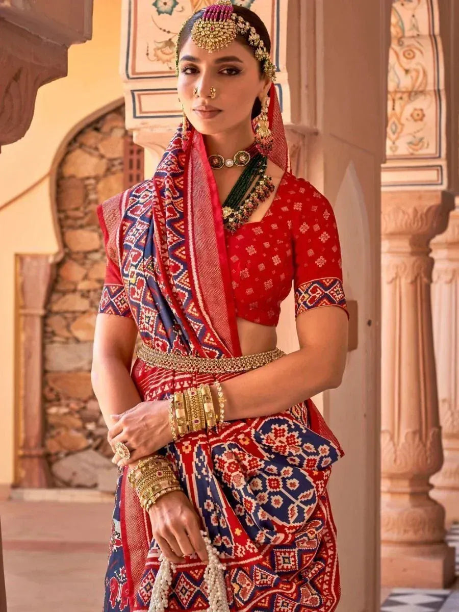 Red and blue printed saree with ethnic jewelry, perfect for Indian weddings or festive occasions