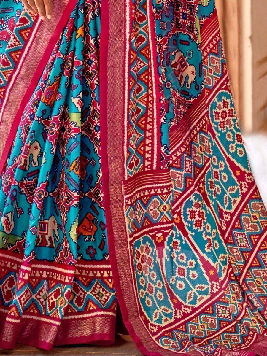 Vibrant turquoise and red ethnic saree with elephant motifs and geometric patterns, perfect for festive occasions.