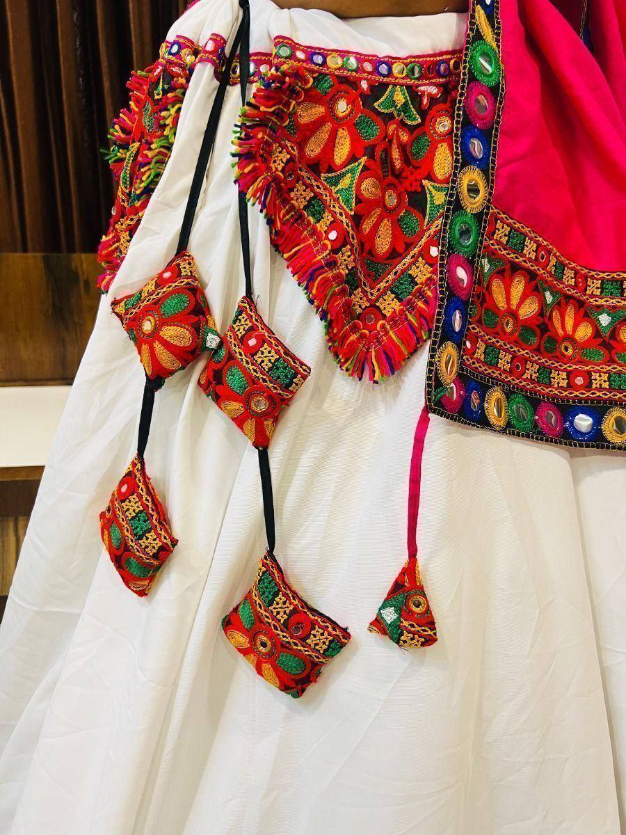 White ethnic lehenga with vibrant mirror work, colorful embroidery, and tassels for festive occasions