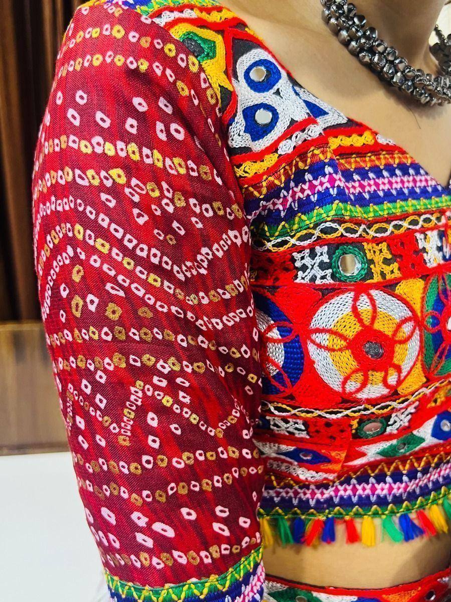 Vibrant red ethnic blouse with mirror work, embroidery, and colorful tassels for traditional Indian wear