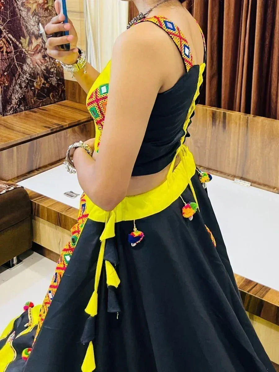 Black and yellow ethnic lehenga choli with colorful embroidery and pom-pom details, perfect for festive occasions