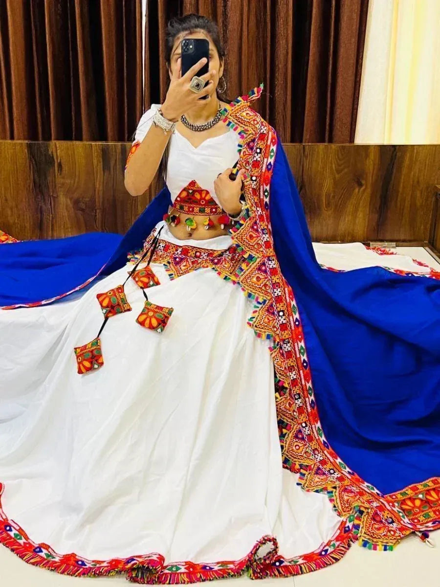 White embroidered lehenga with blue dupatta, colorful mirror work, and traditional Indian ethnic wear