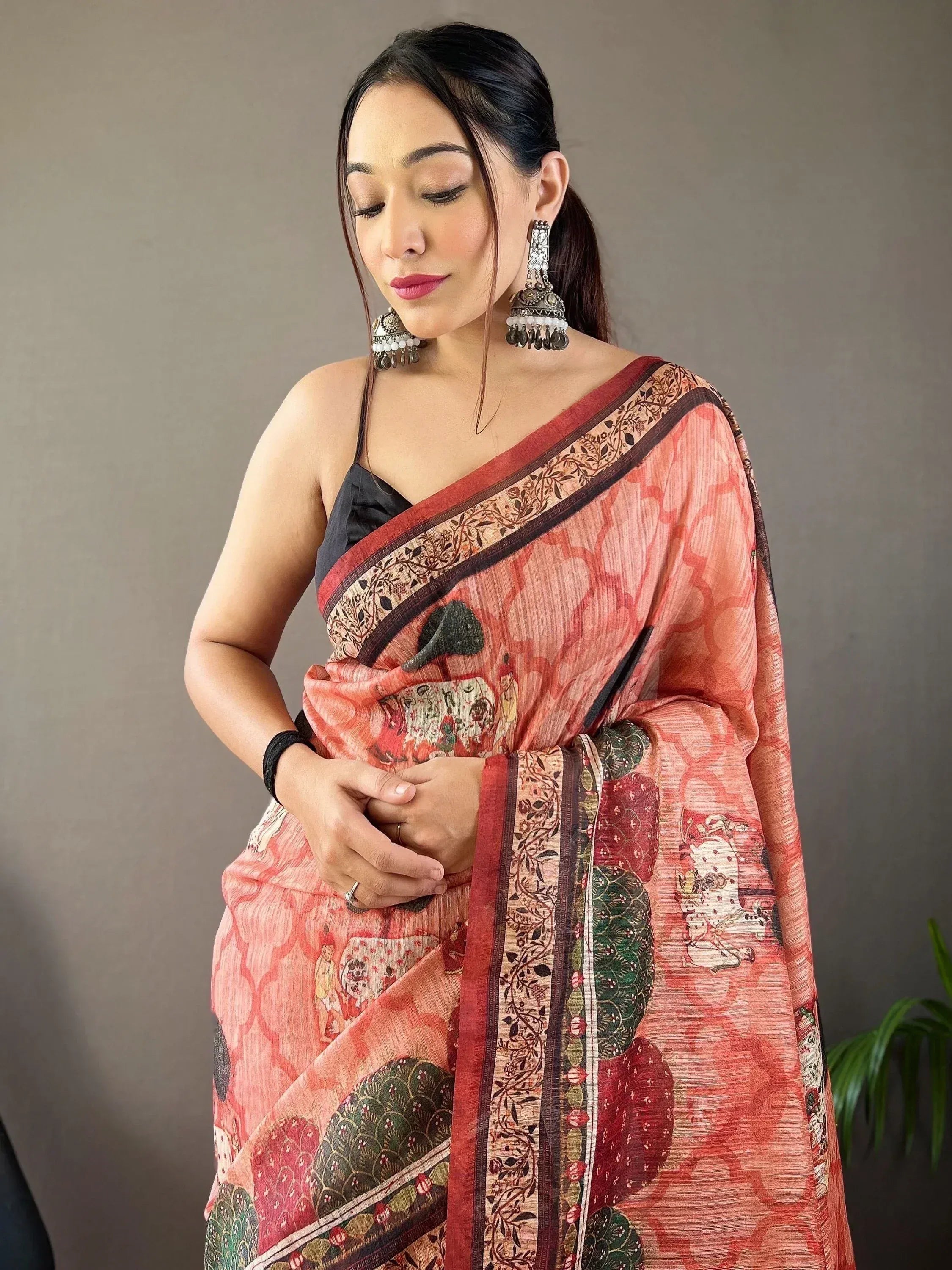 Woman in elegant printed saree with floral border, traditional Indian ethnic wear, paired with jhumka earrings