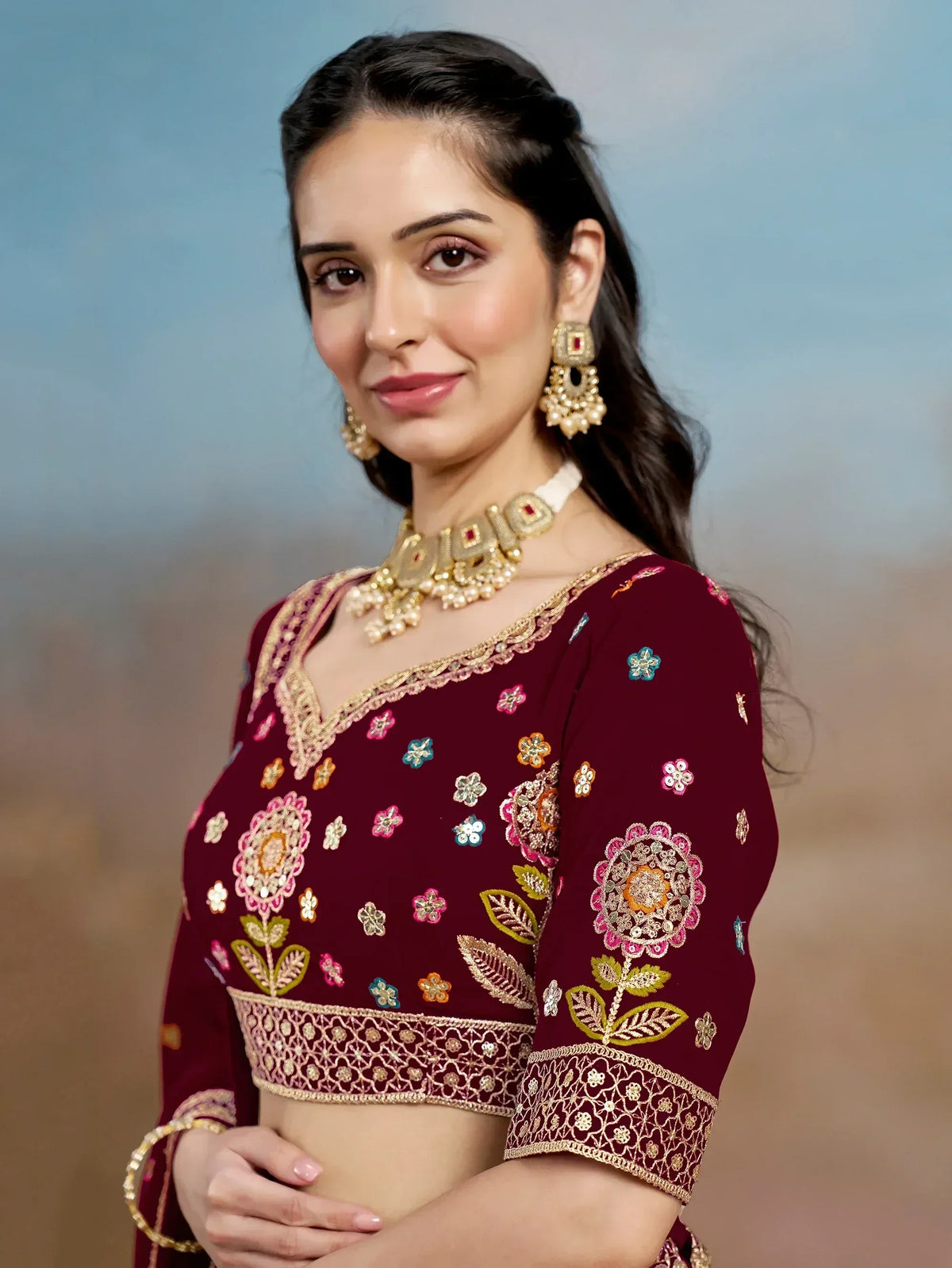 Maroon embroidered blouse with floral motifs, gold detailing, and traditional Indian jewelry for ethnic wear