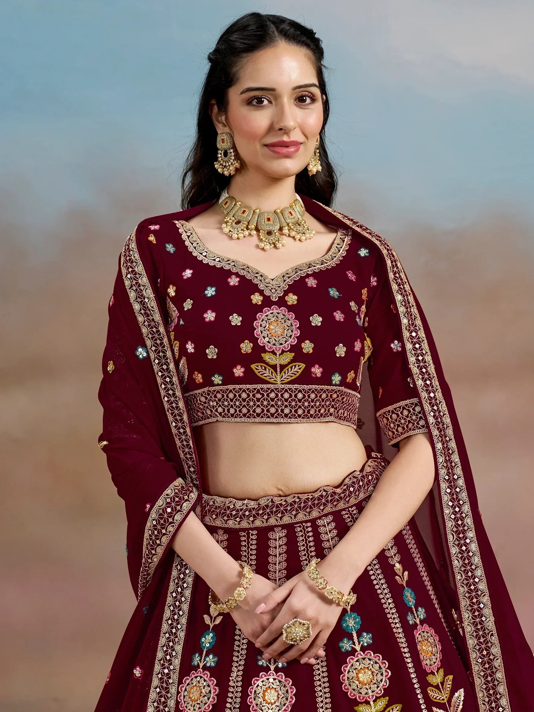 Maroon embroidered lehenga choli with floral motifs and gold detailing, perfect for Indian ethnic wear occasions.