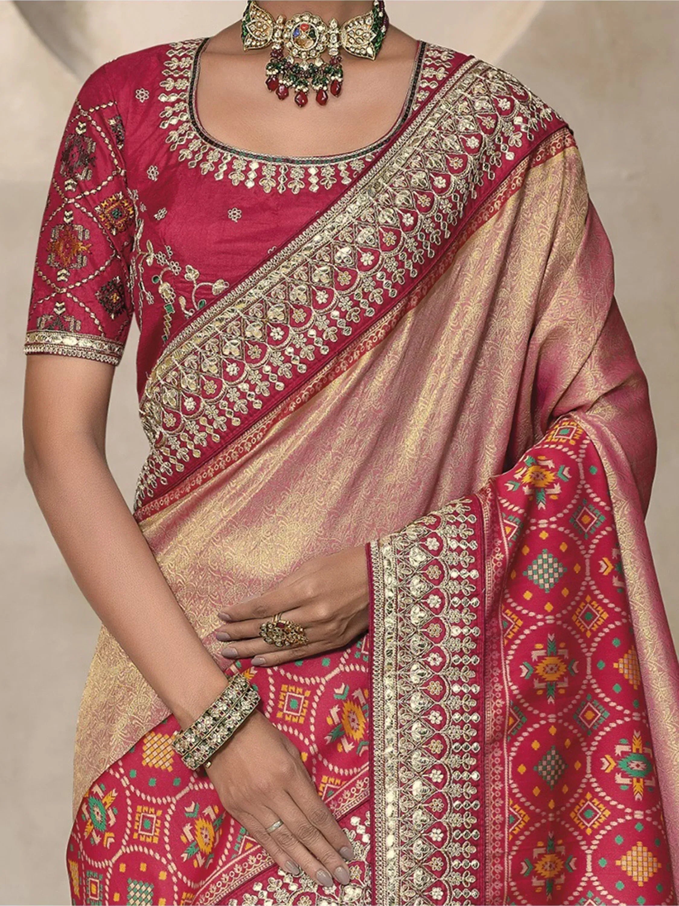 Elegant maroon saree with gold embroidery and geometric patterns, paired with traditional jewelry for ethnic wear.