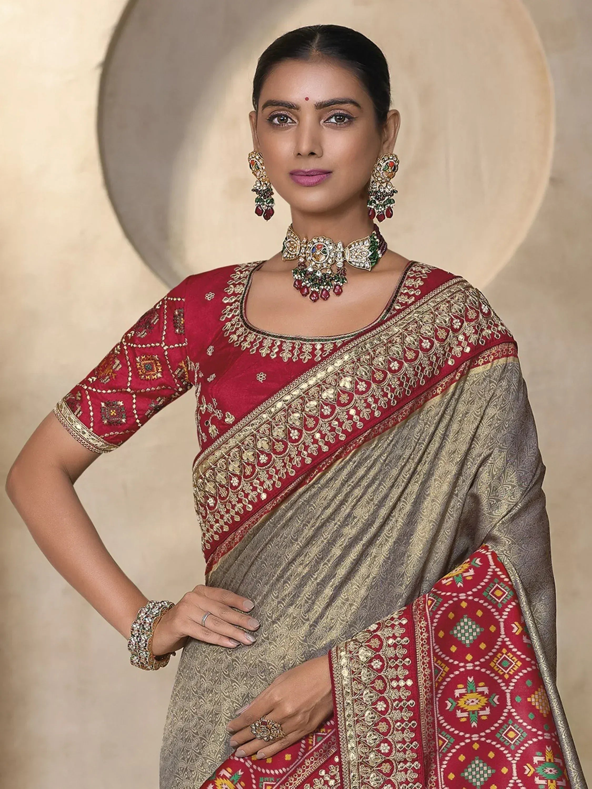 Elegant Indian saree with red and gold embroidery, paired with traditional jewelry for festive occasions.