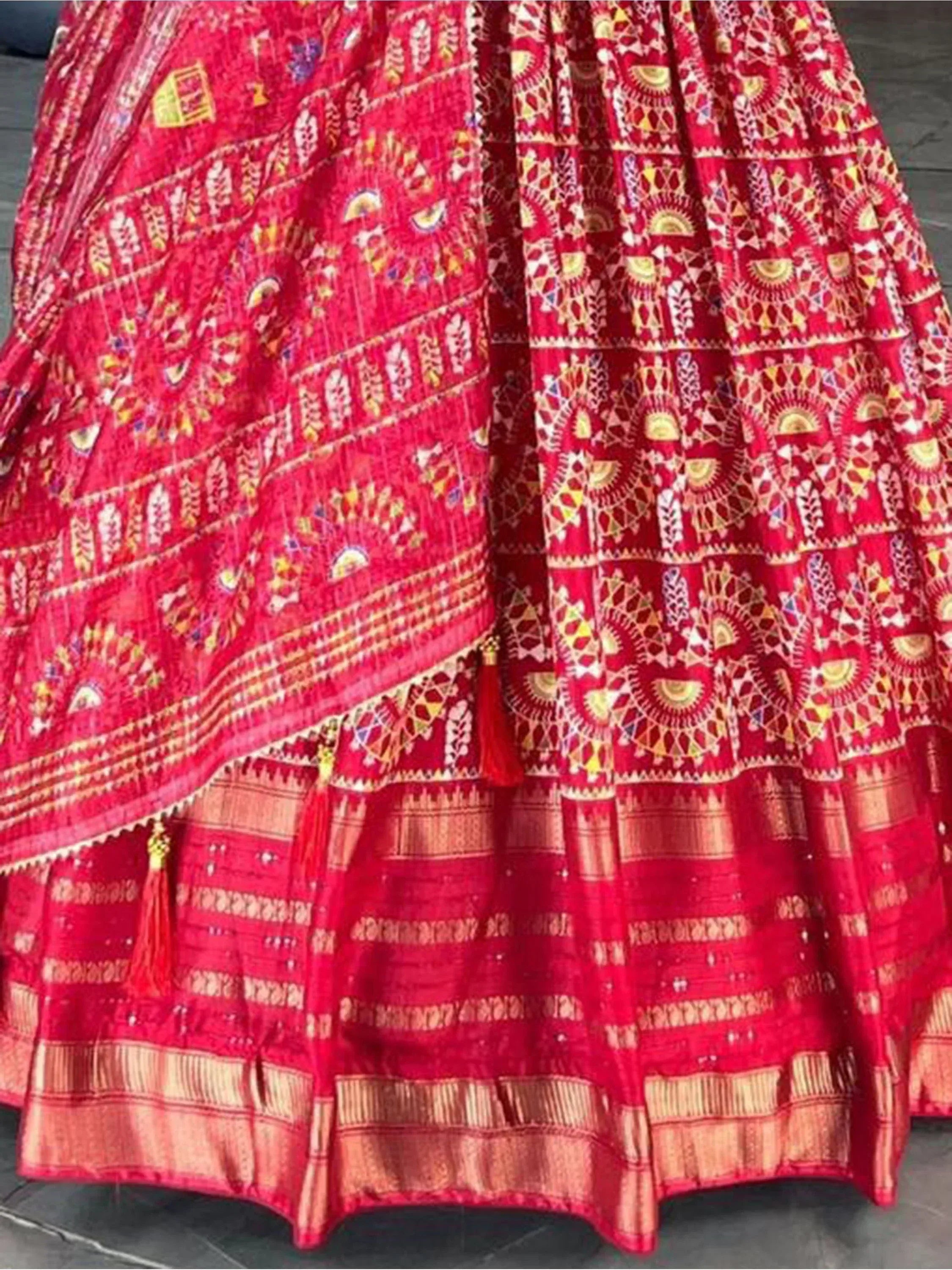 Red embroidered lehenga choli with intricate gold patterns and tassels, ideal for Indian ethnic wear