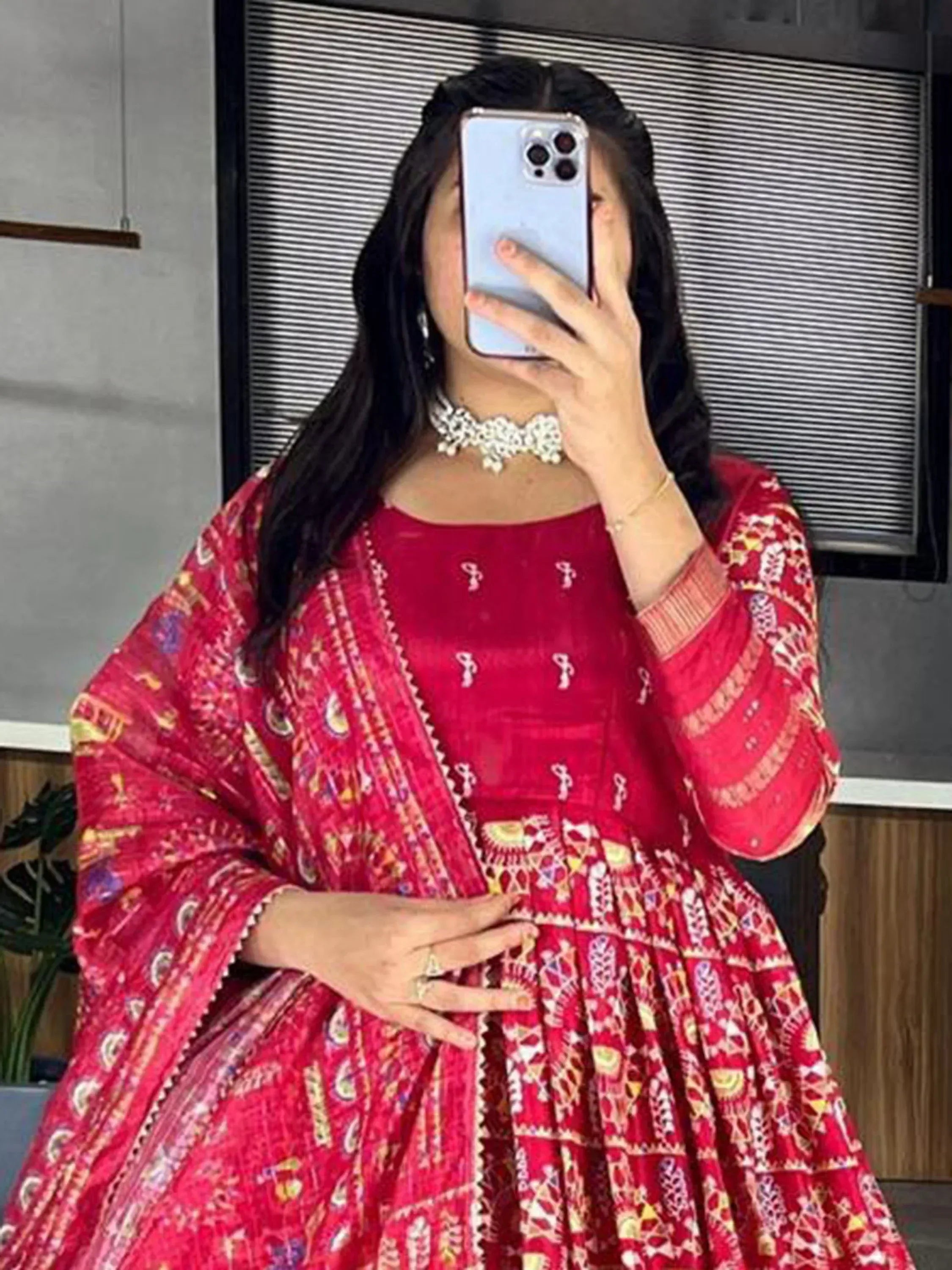 Woman in red ethnic gown with printed dupatta, taking mirror selfie, perfect for Indian occasions