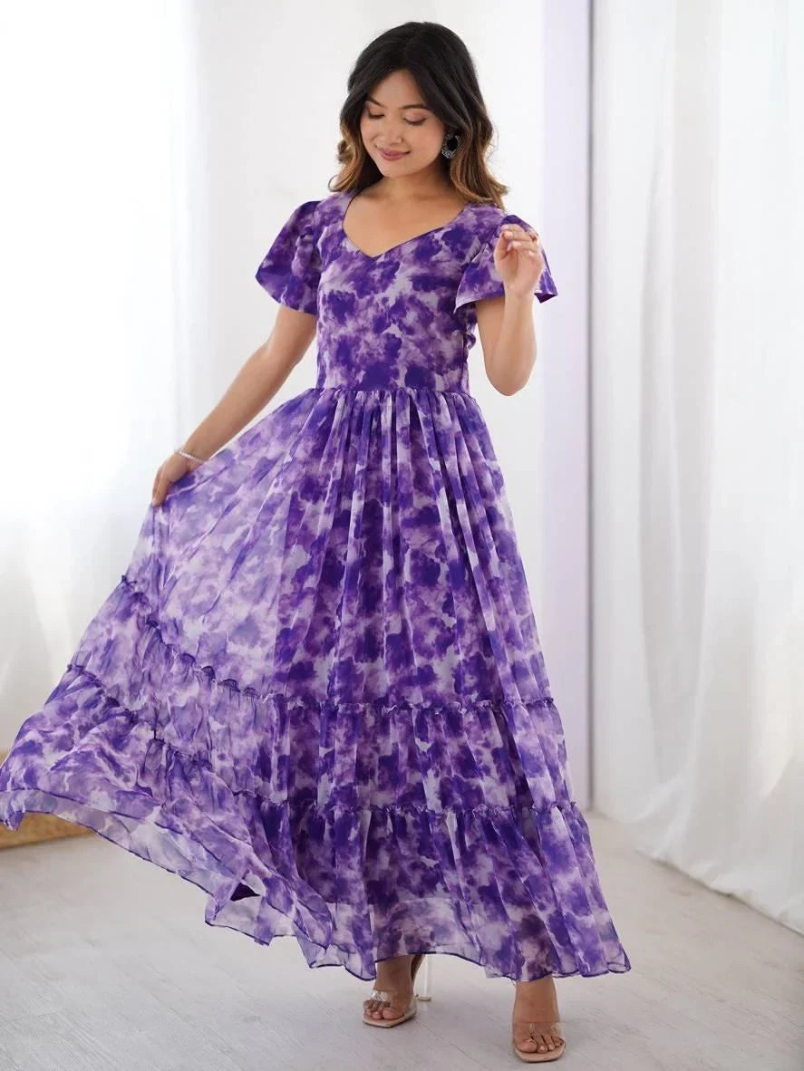 Woman wearing a flowing purple tie-dye ethnic gown with flutter sleeves indoors