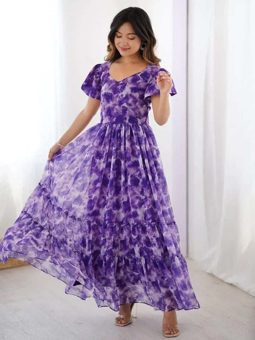 Woman wearing a flowing purple tie-dye ethnic gown with flutter sleeves indoors
