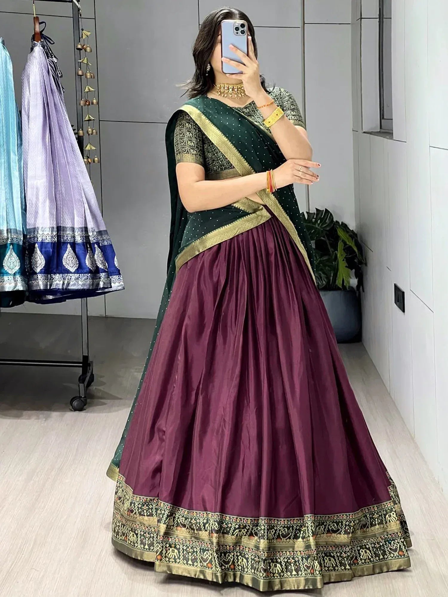 Woman in maroon lehenga choli with green dupatta, gold border, and elephant print, perfect for Indian ethnic wear.