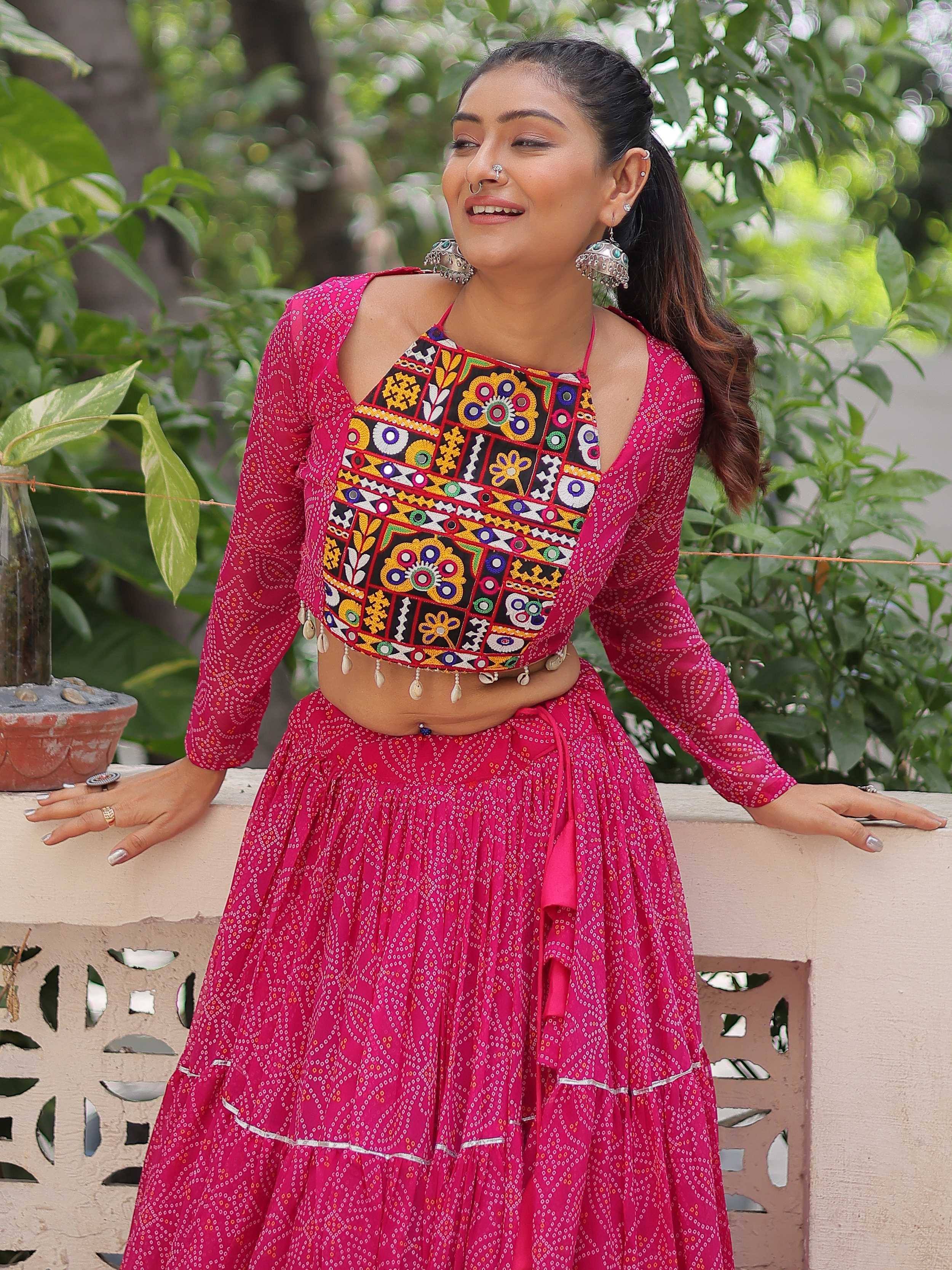 Vibrant pink ethnic lehenga choli with colorful mirror work and floral embroidery, perfect for festive occasions.