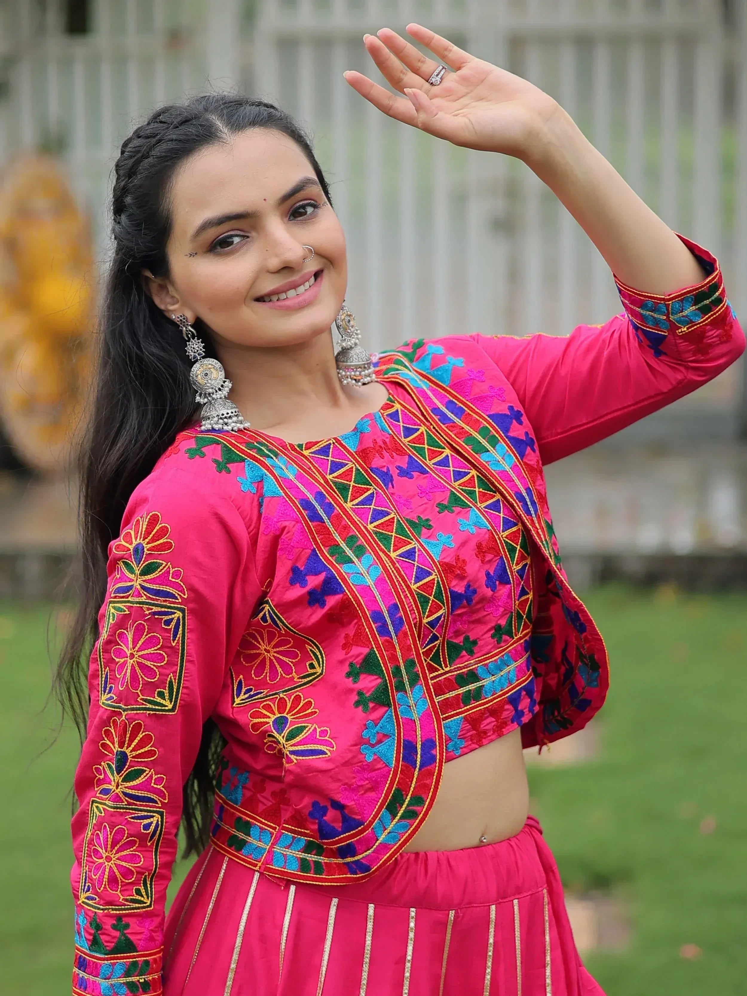 Woman in vibrant pink embroidered Indian ethnic wear with floral patterns and traditional jewelry