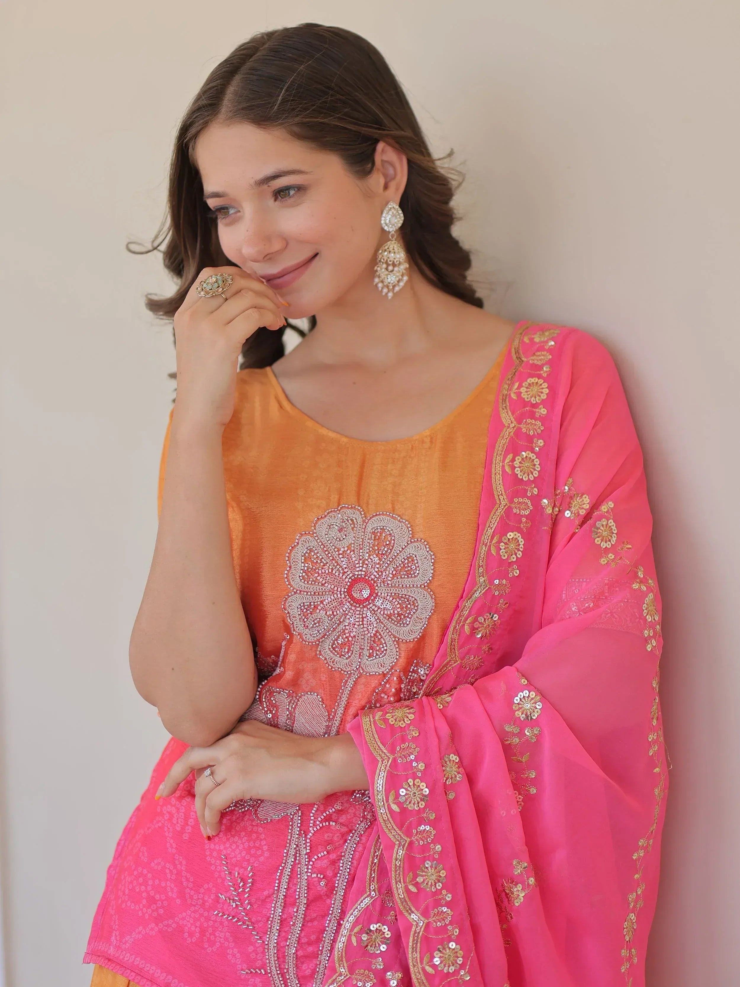 Woman in orange and pink embroidered salwar kameez with floral sequin design and matching dupatta