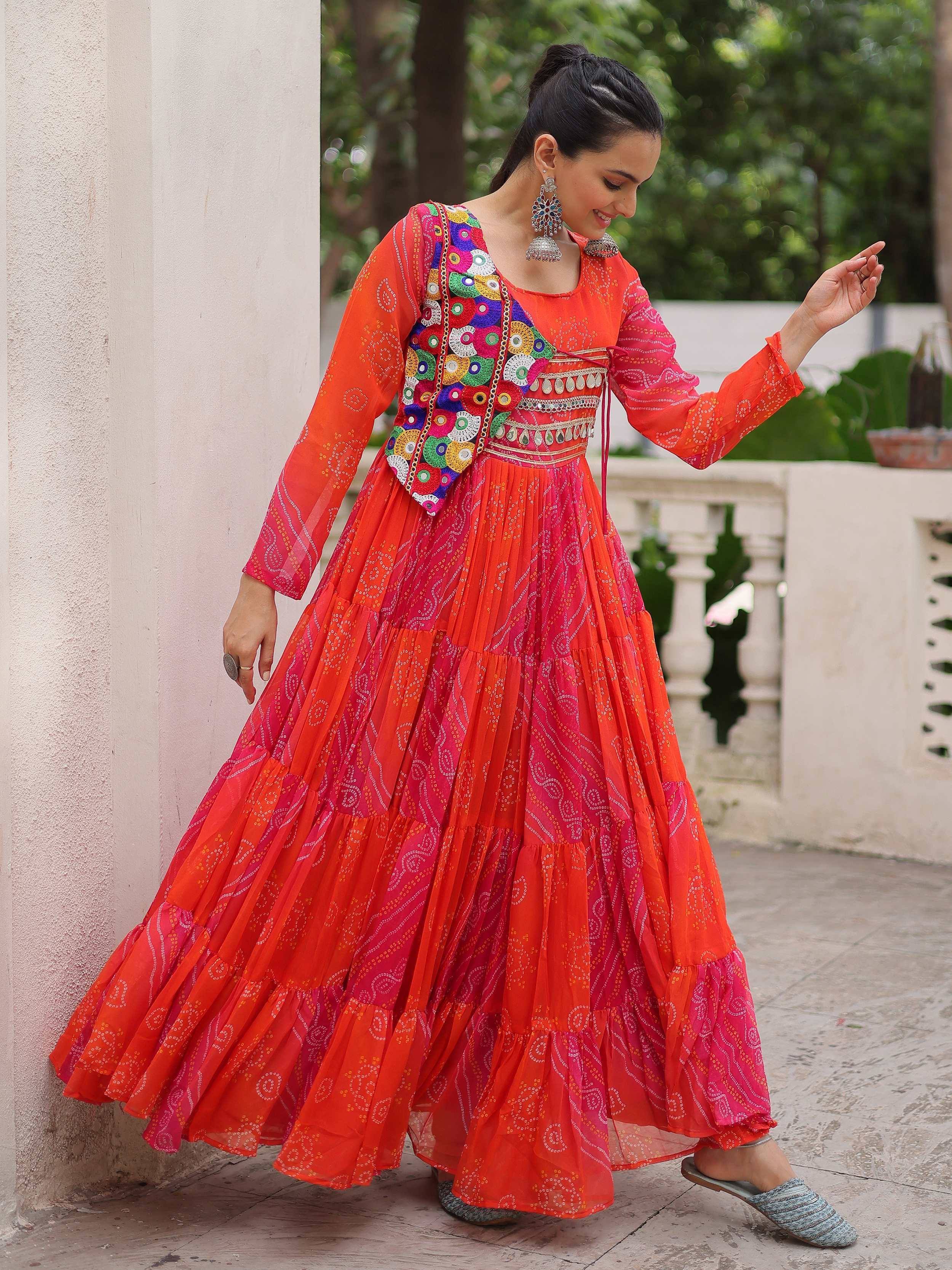 Vibrant orange and pink ethnic gown with mirror work, perfect for Indian festivals and occasions.