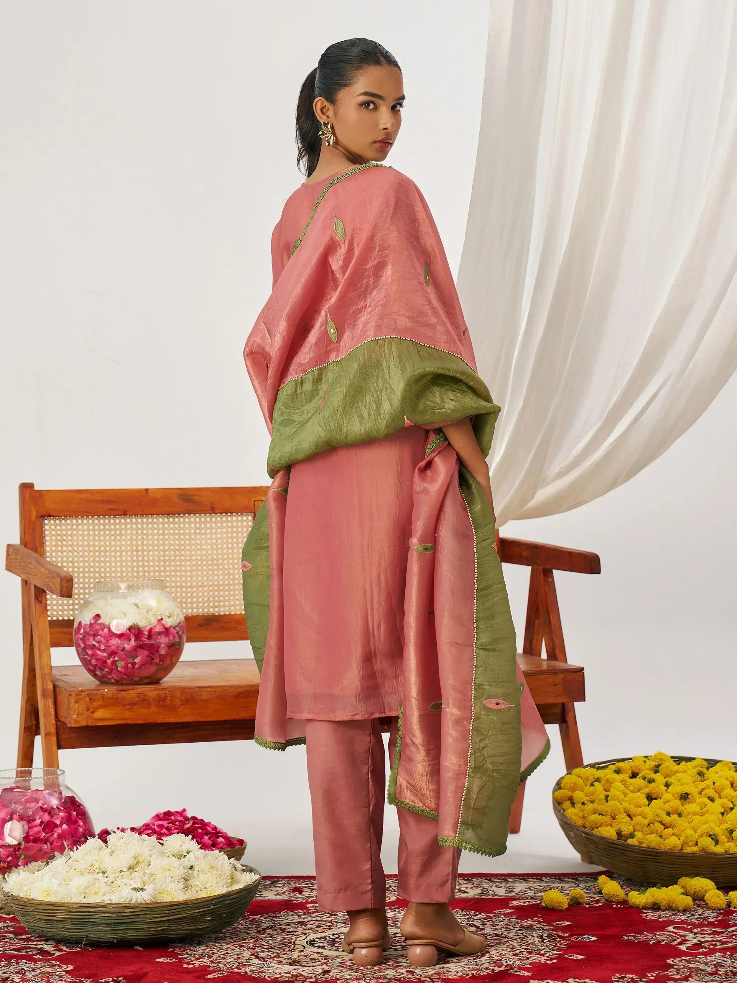 Pink and green ethnic salwar kameez with leaf embroidery, styled with floral decor for festive occasions