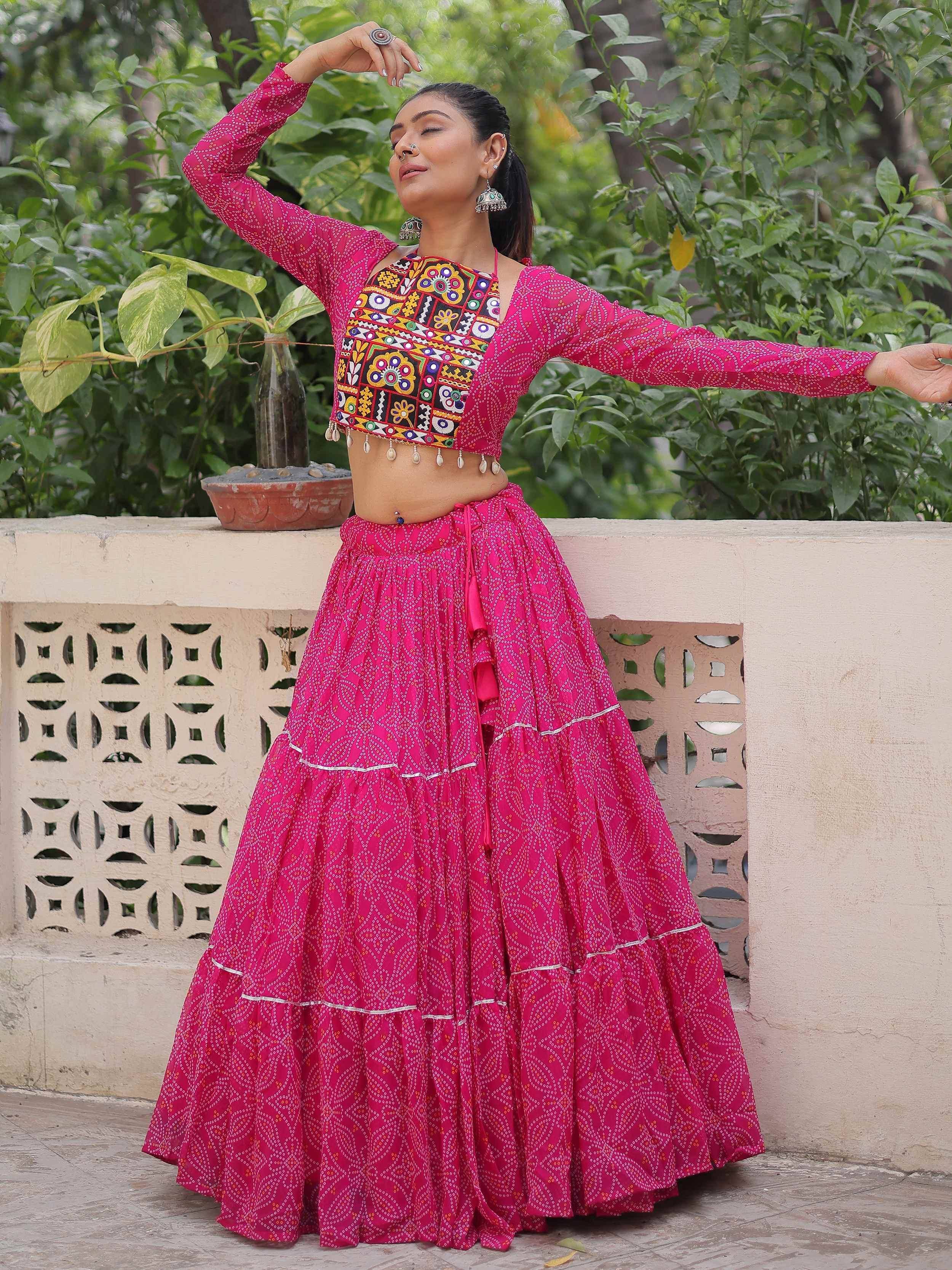Woman in vibrant pink ethnic lehenga choli with mirror work, perfect for Indian festivals and celebrations.