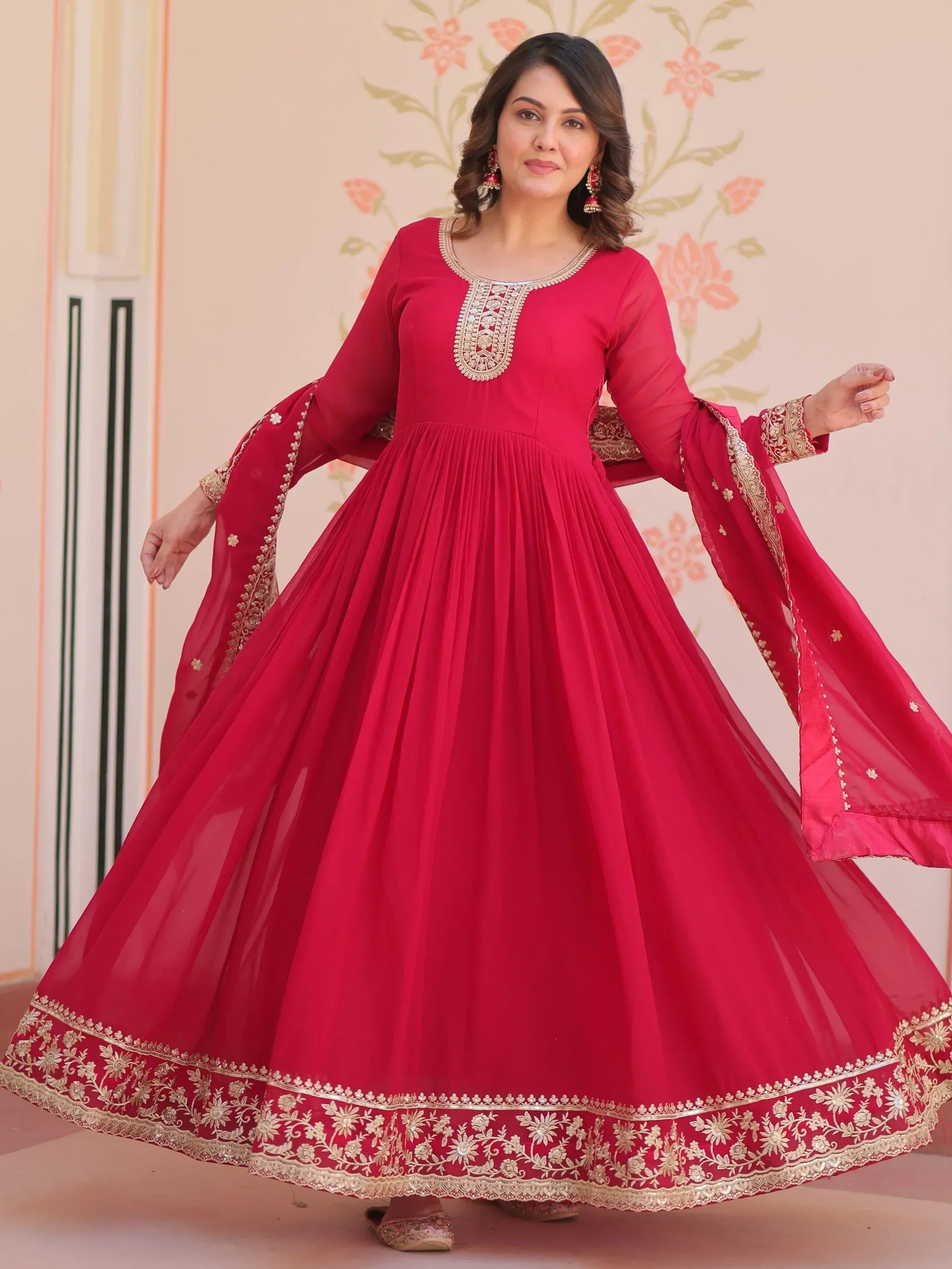 Red ethnic gown with gold embroidery, flared skirt, and bell sleeves for Indian occasions