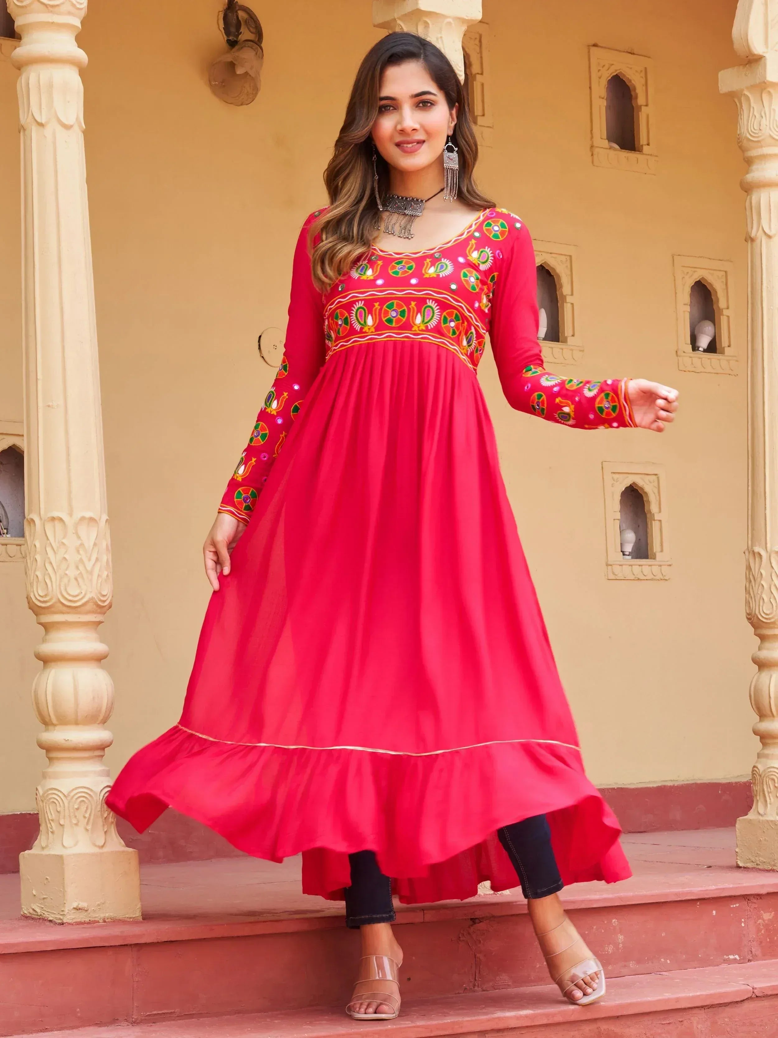 Vibrant red ethnic gown with colorful embroidery, perfect for Indian festive occasions.
