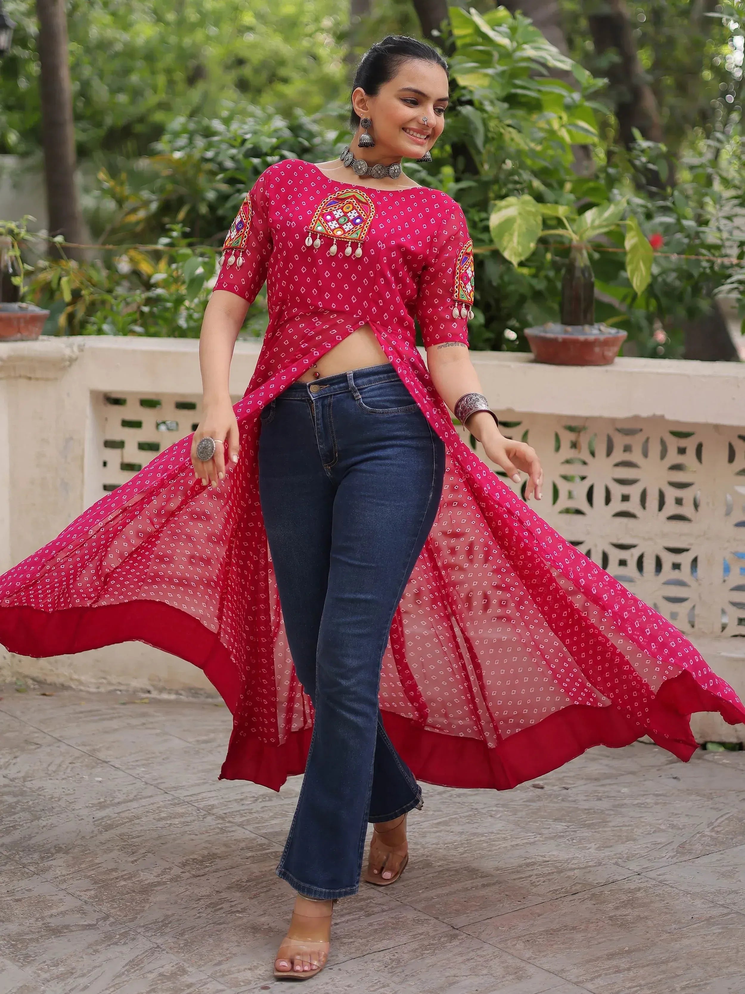 Woman in red embroidered ethnic top with flared hem, paired with blue jeans, styled for Indian fashion