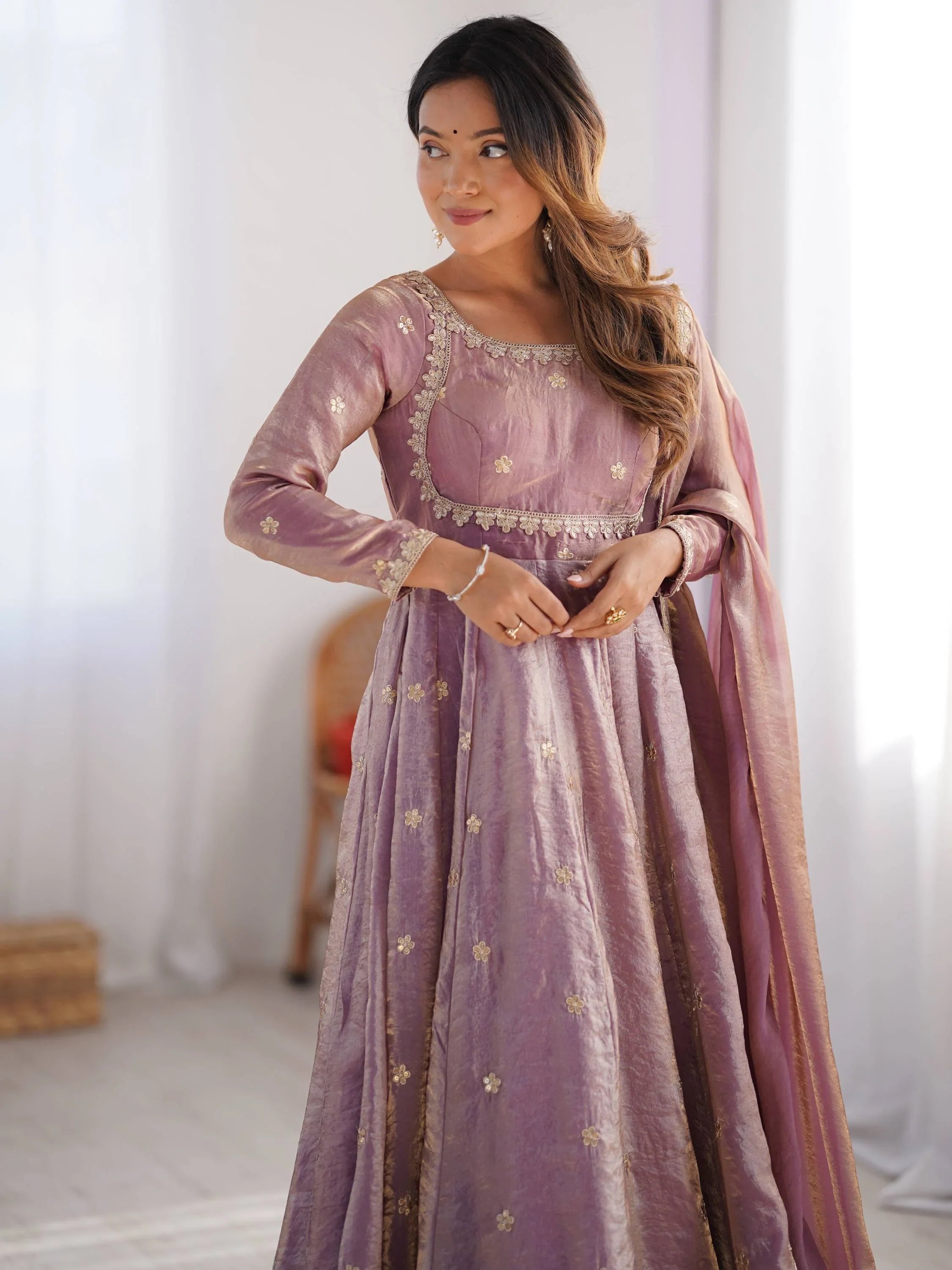 Woman wearing pastel pink embroidered ethnic gown with dupatta, elegant Indian attire