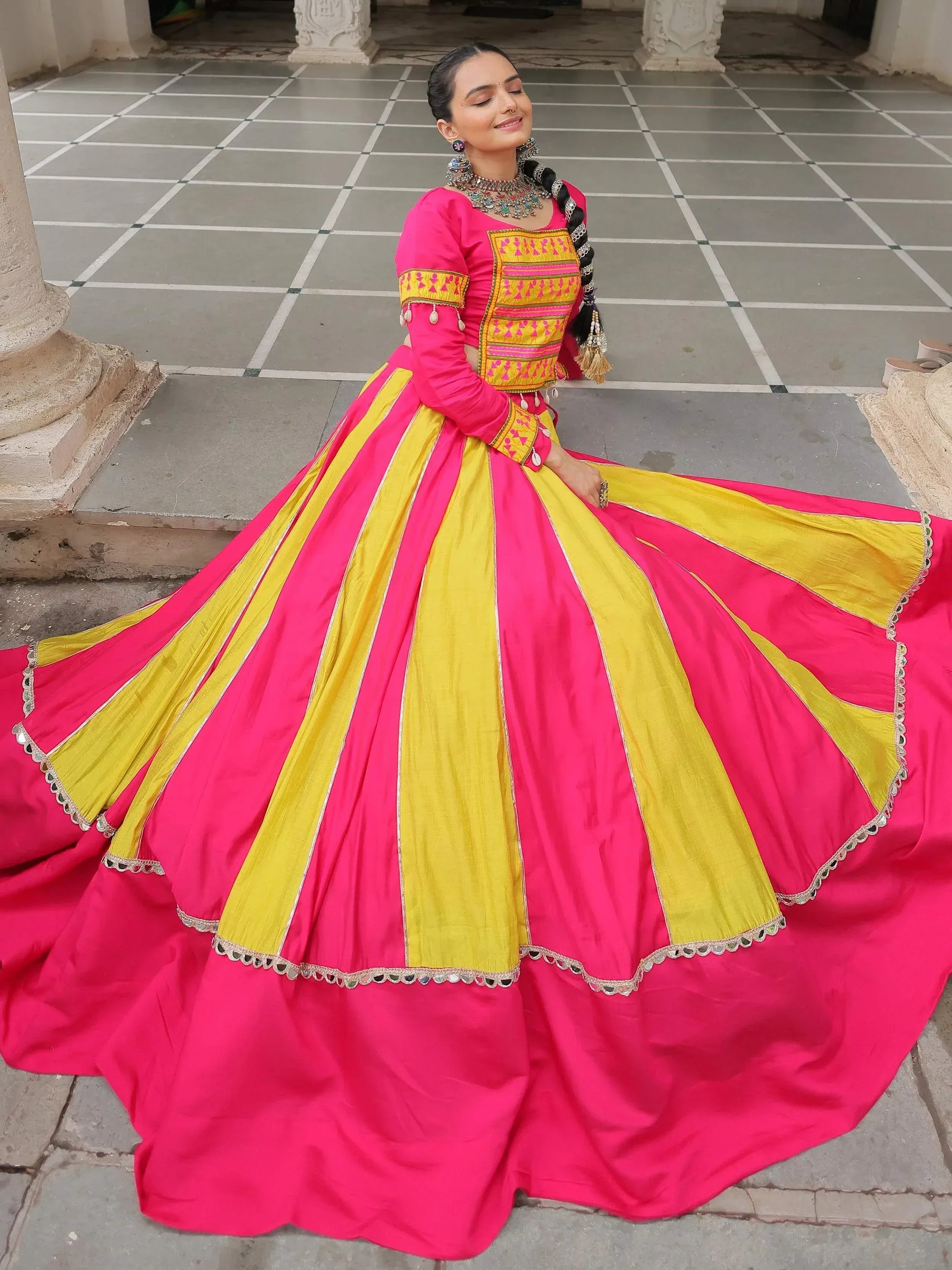 Vibrant pink and yellow ethnic lehenga choli with intricate embroidery and mirror work