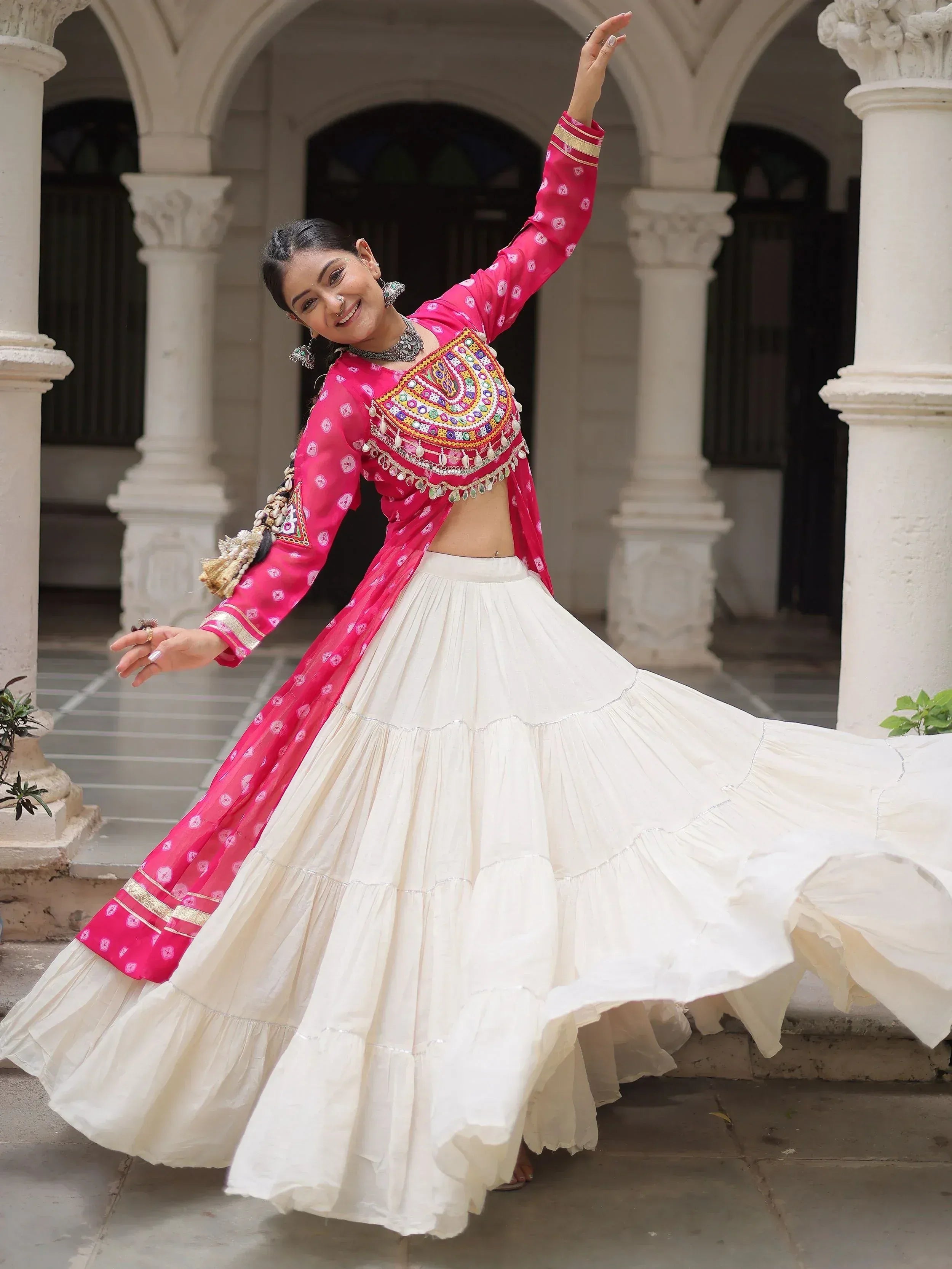 Woman in pink embroidered choli and white flared lehenga dancing in courtyard